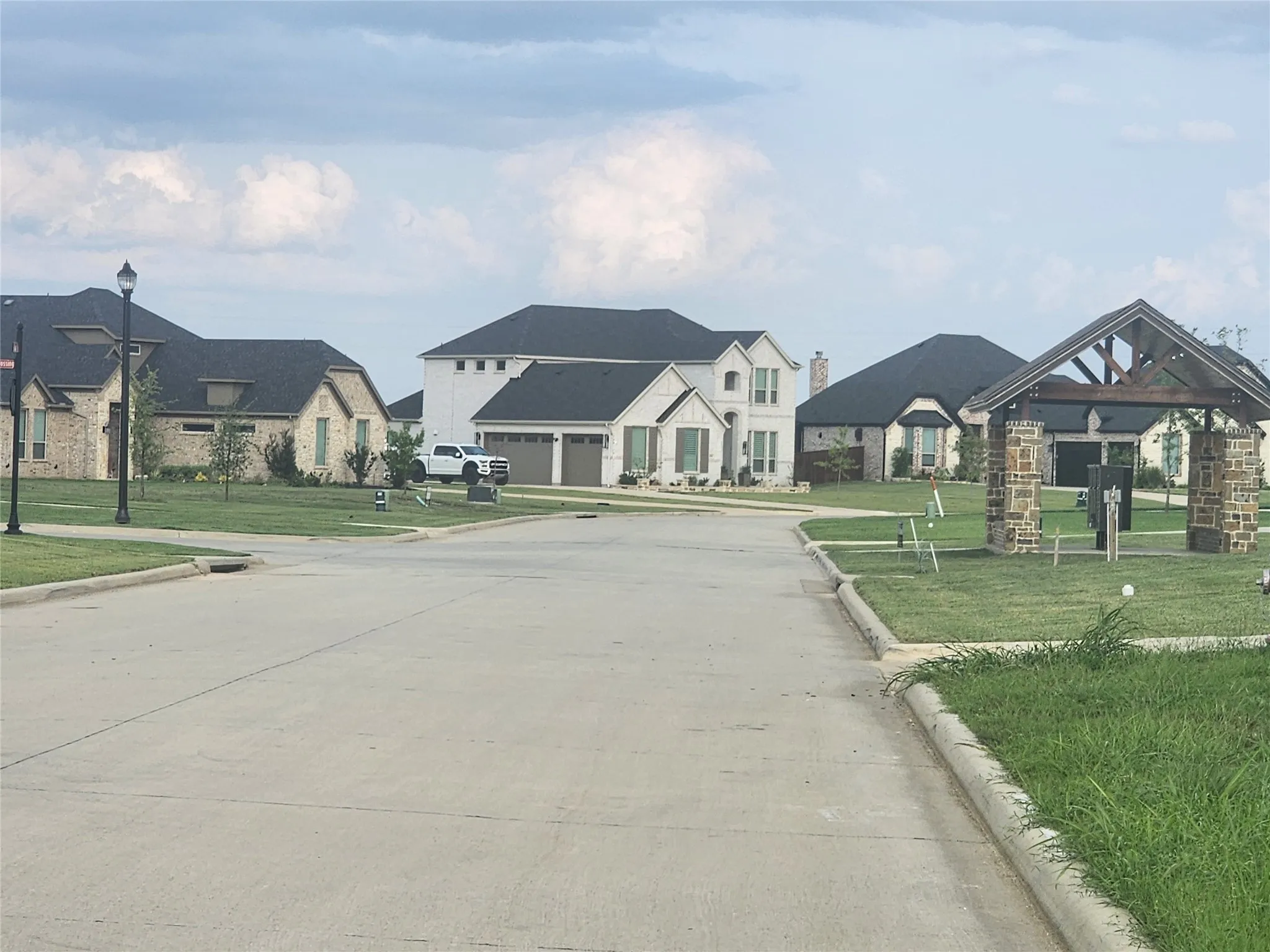 View of concrete road featuring curbs, a residential view, and street lighting