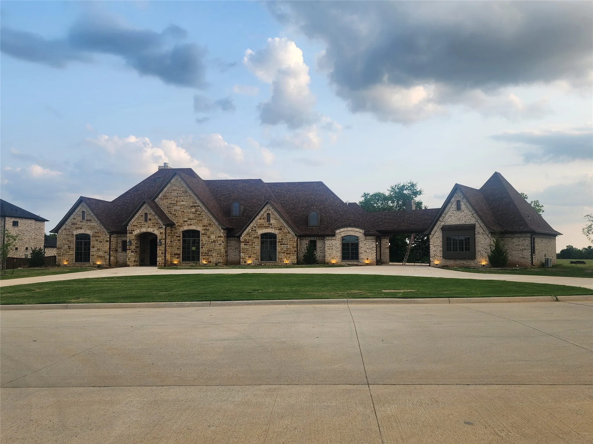 French country style house featuring curved driveway, a front yard, and stone siding