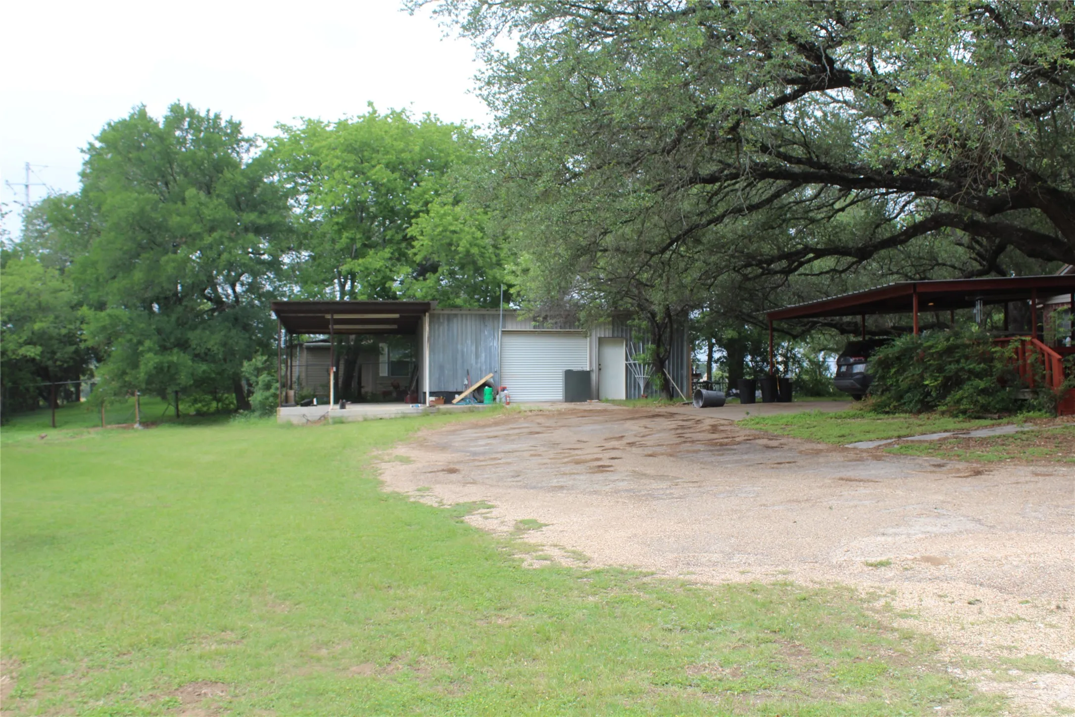 Expansive gravel driveway with a large carport