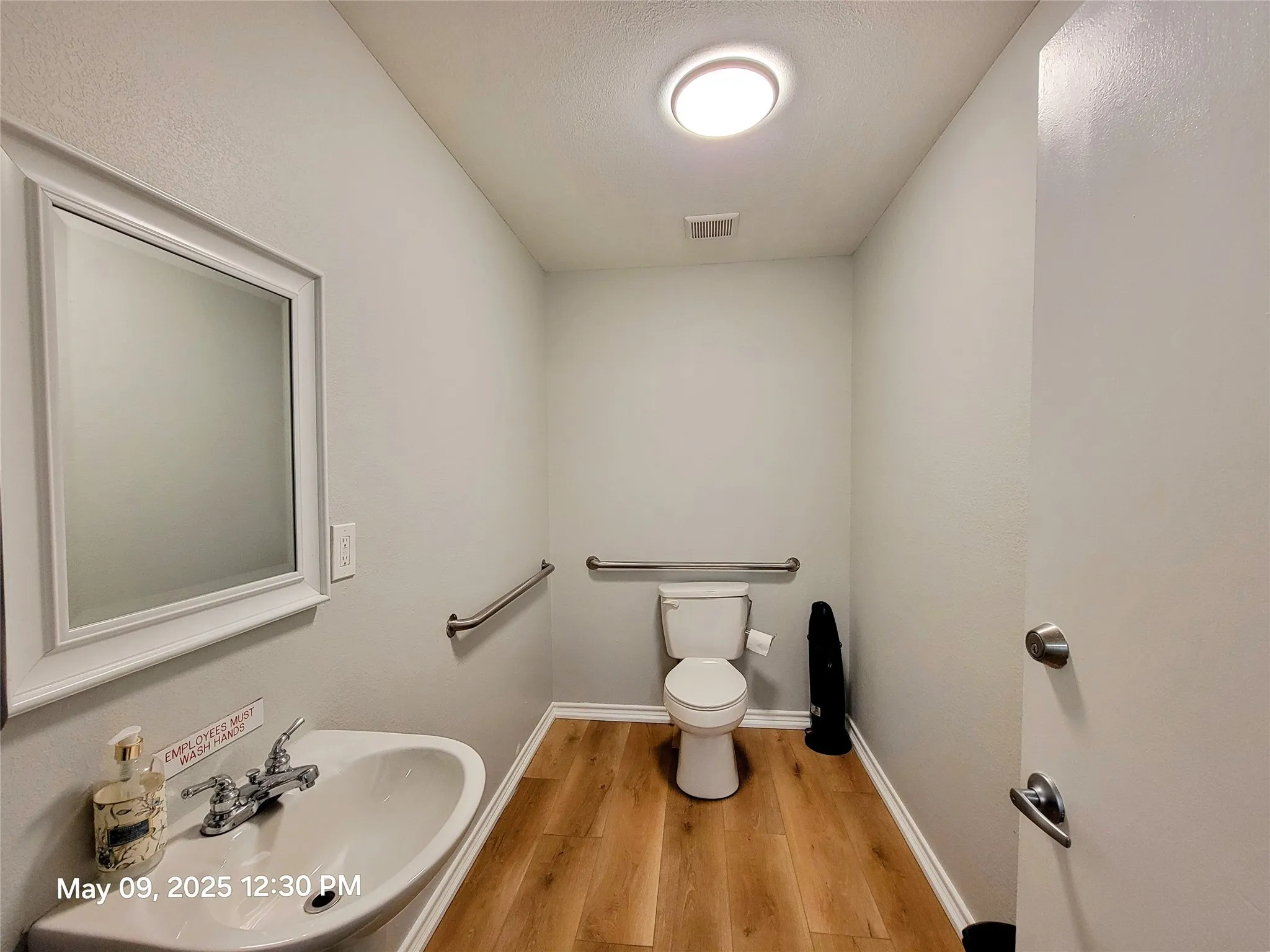Bathroom featuring a sink, toilet, wood finished floors, and baseboards