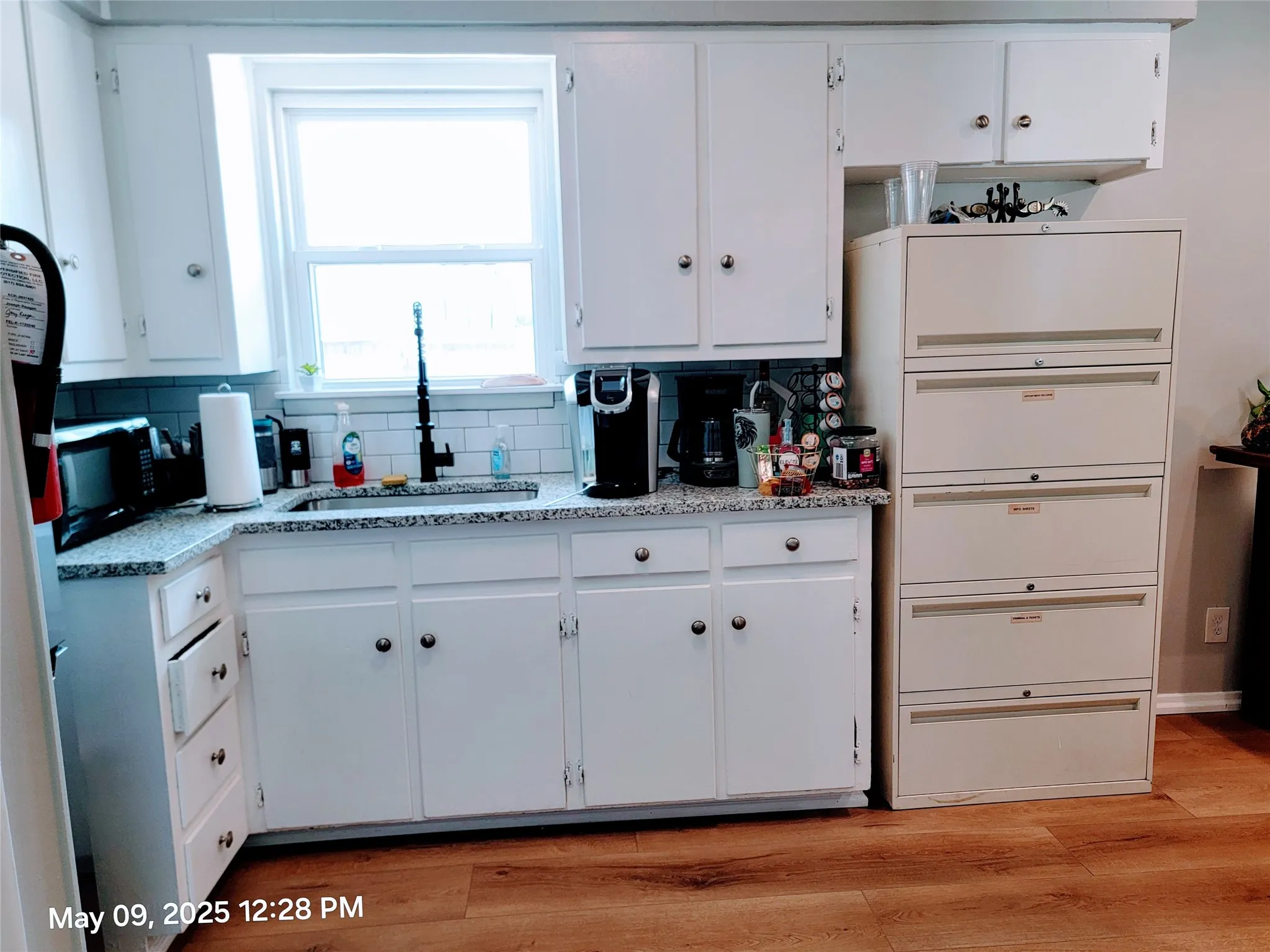 Kitchen featuring a sink, white cabinets, backsplash, and black microwave