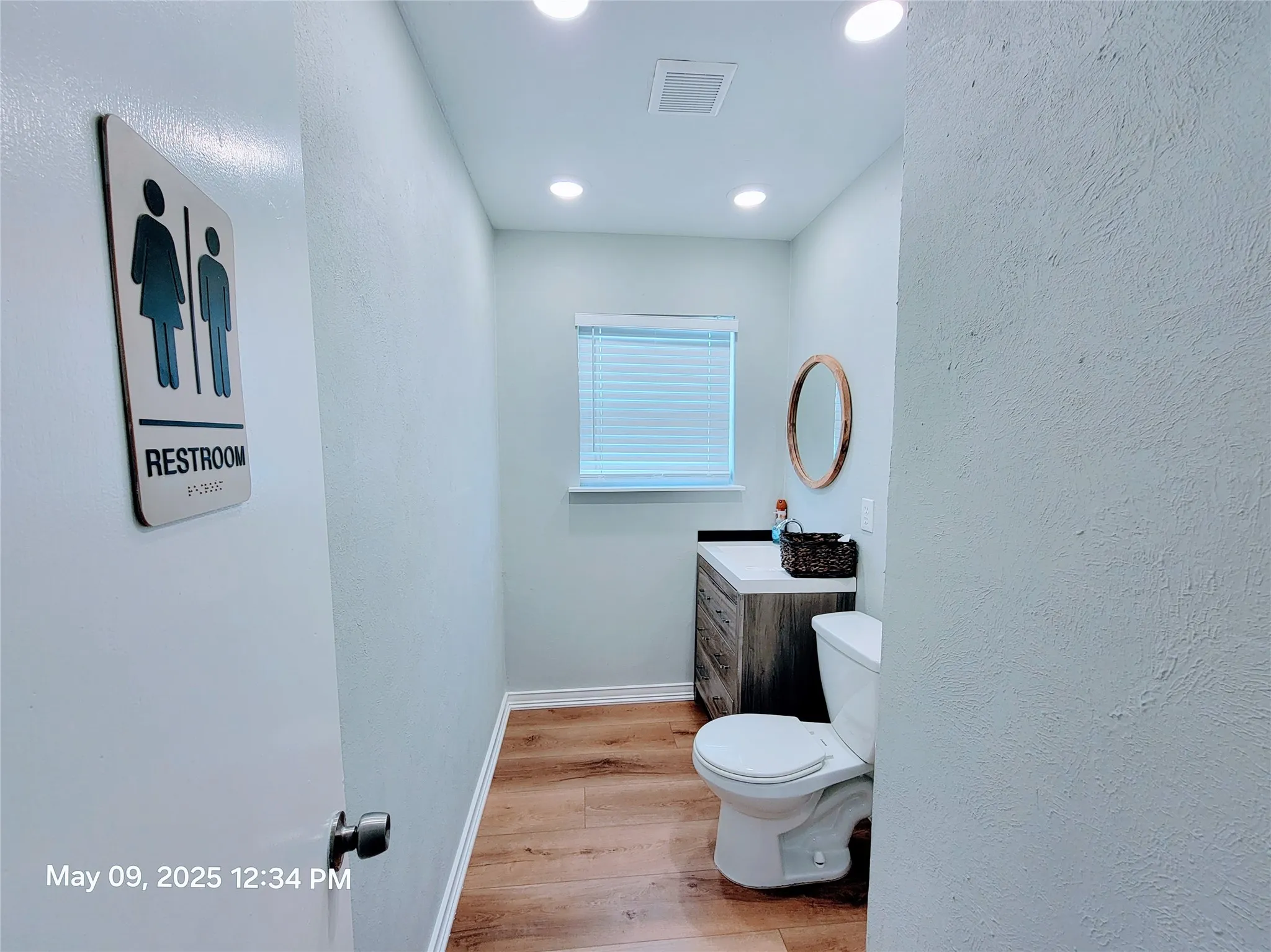 Bathroom featuring wood finished floors, toilet, vanity, baseboards, and a textured wall