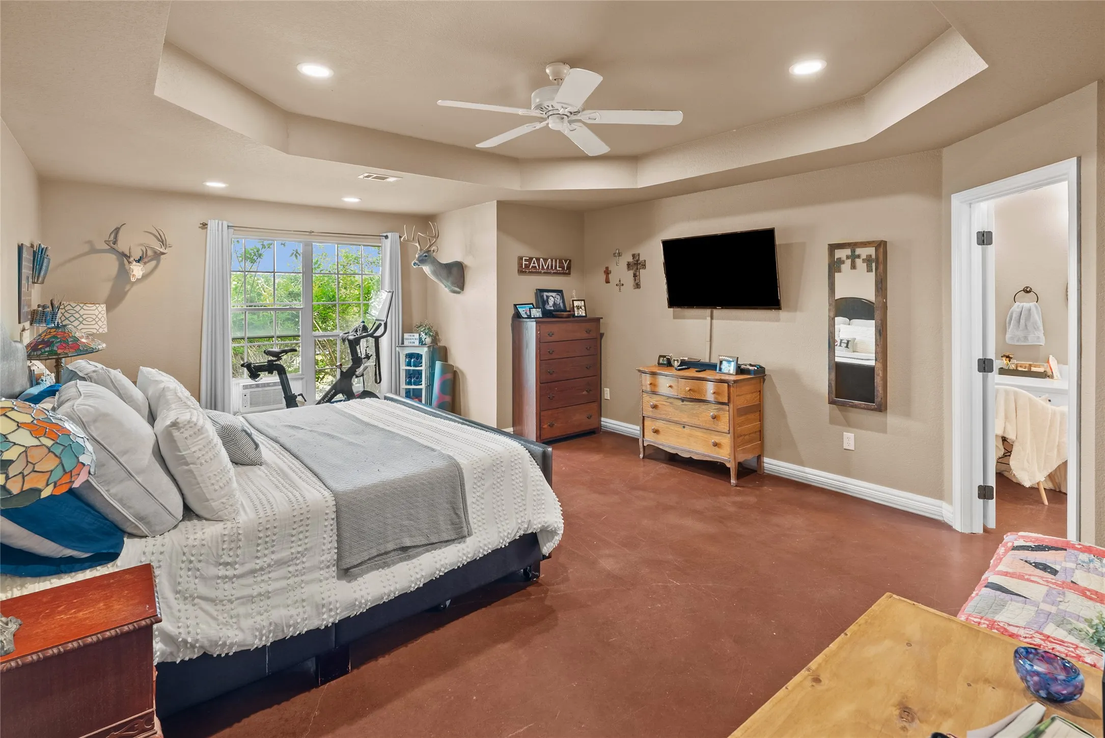 Bedroom with a tray ceiling, baseboards, recessed lighting, concrete flooring, and ceiling fan