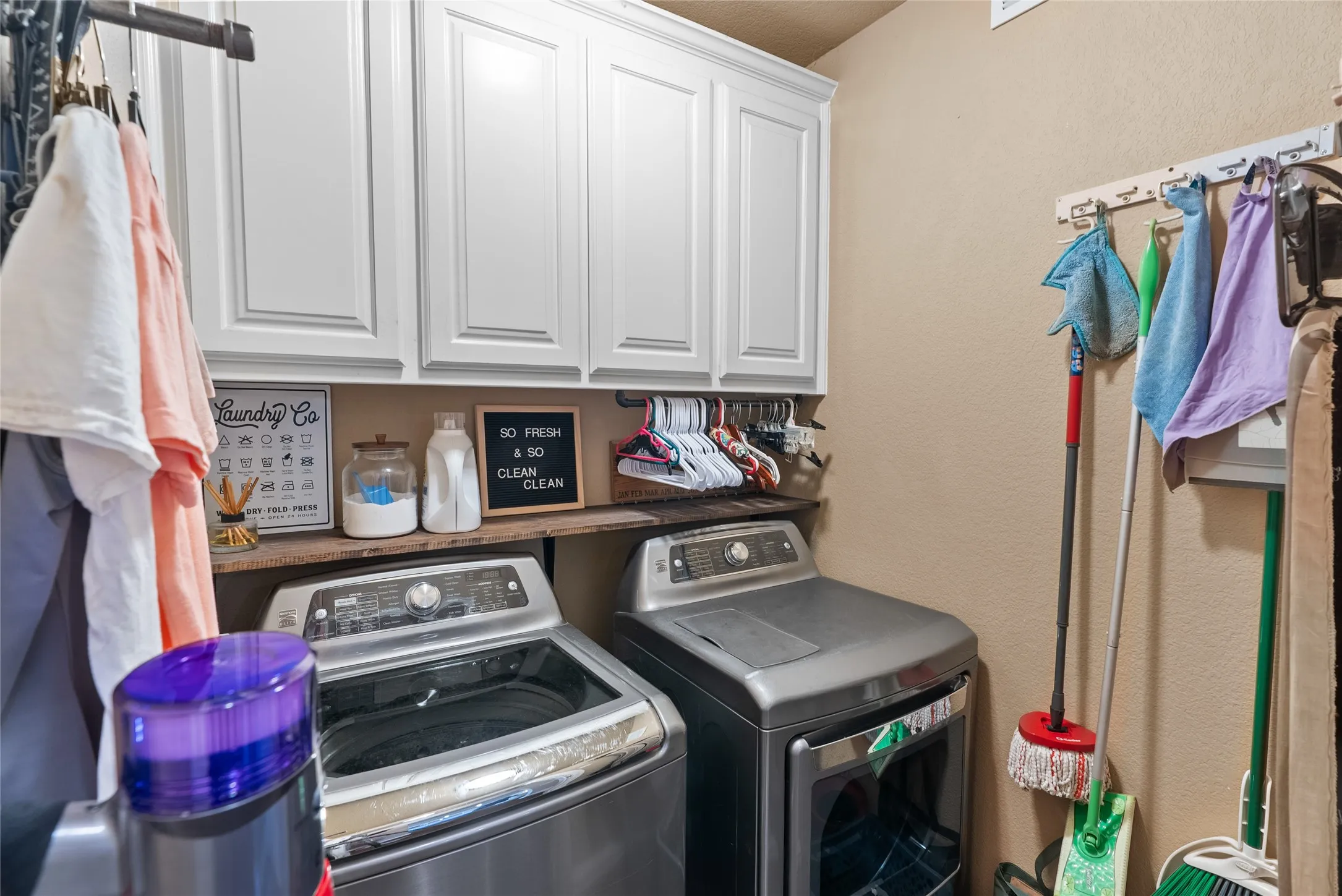 Washroom featuring independent washer and dryer and cabinet space