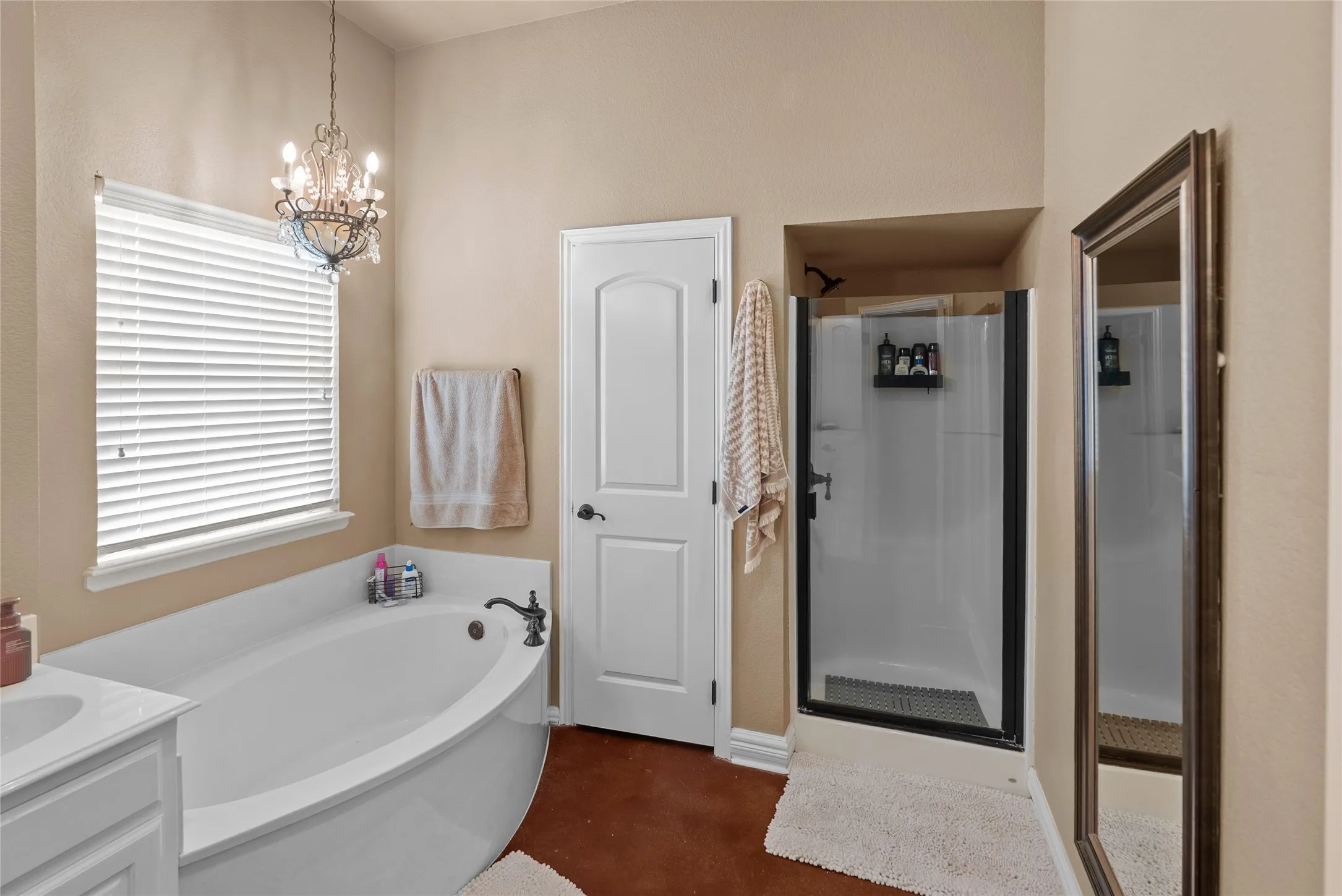 Full bathroom featuring a shower stall, a bath, a chandelier, and vanity