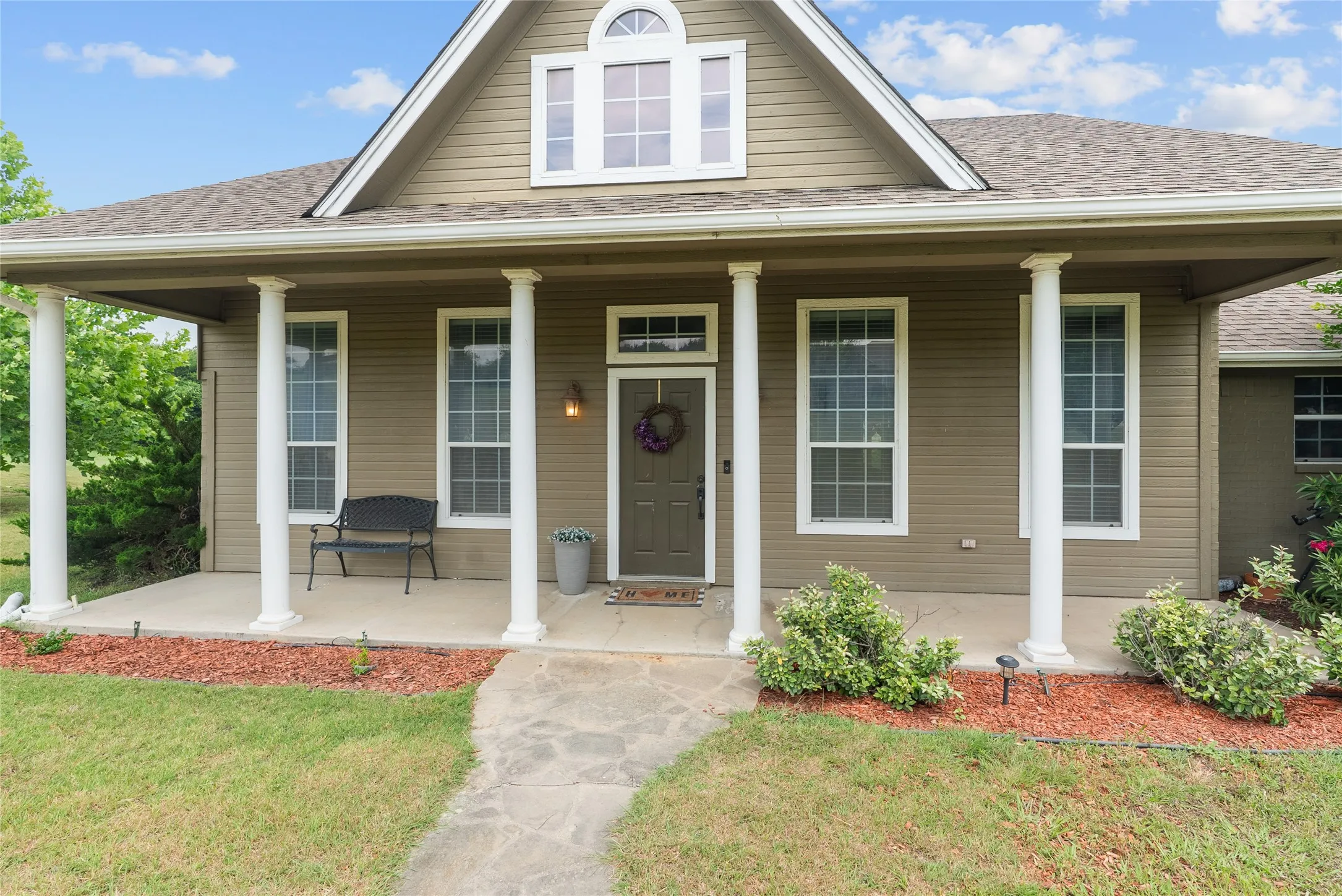 View of front of home with a porch, a shingled roof, and a front lawn
