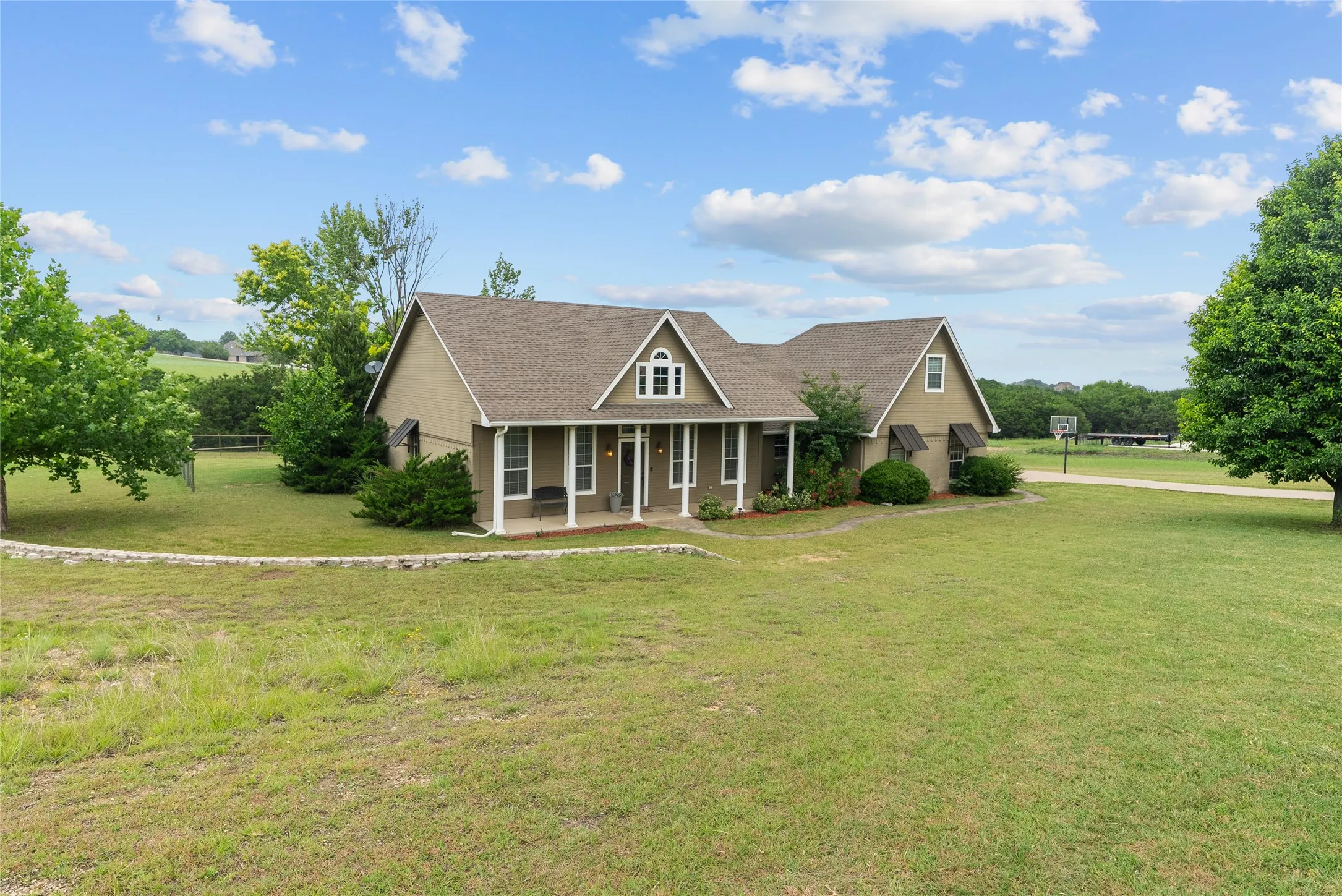 View of front of property with a porch, roof with shingles, and a front lawn