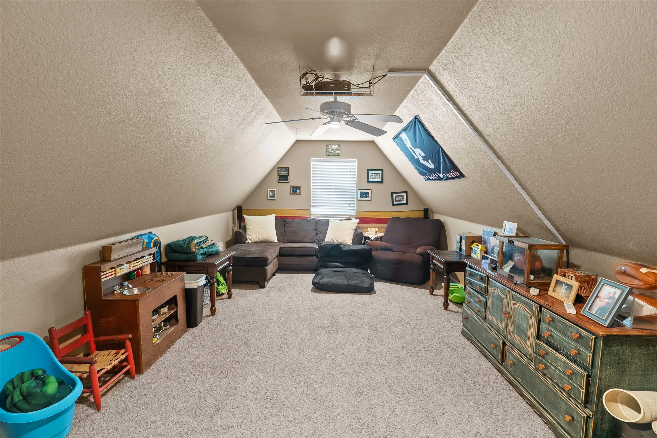 Recreation room with a textured ceiling, a ceiling fan, carpet floors, and vaulted ceiling
