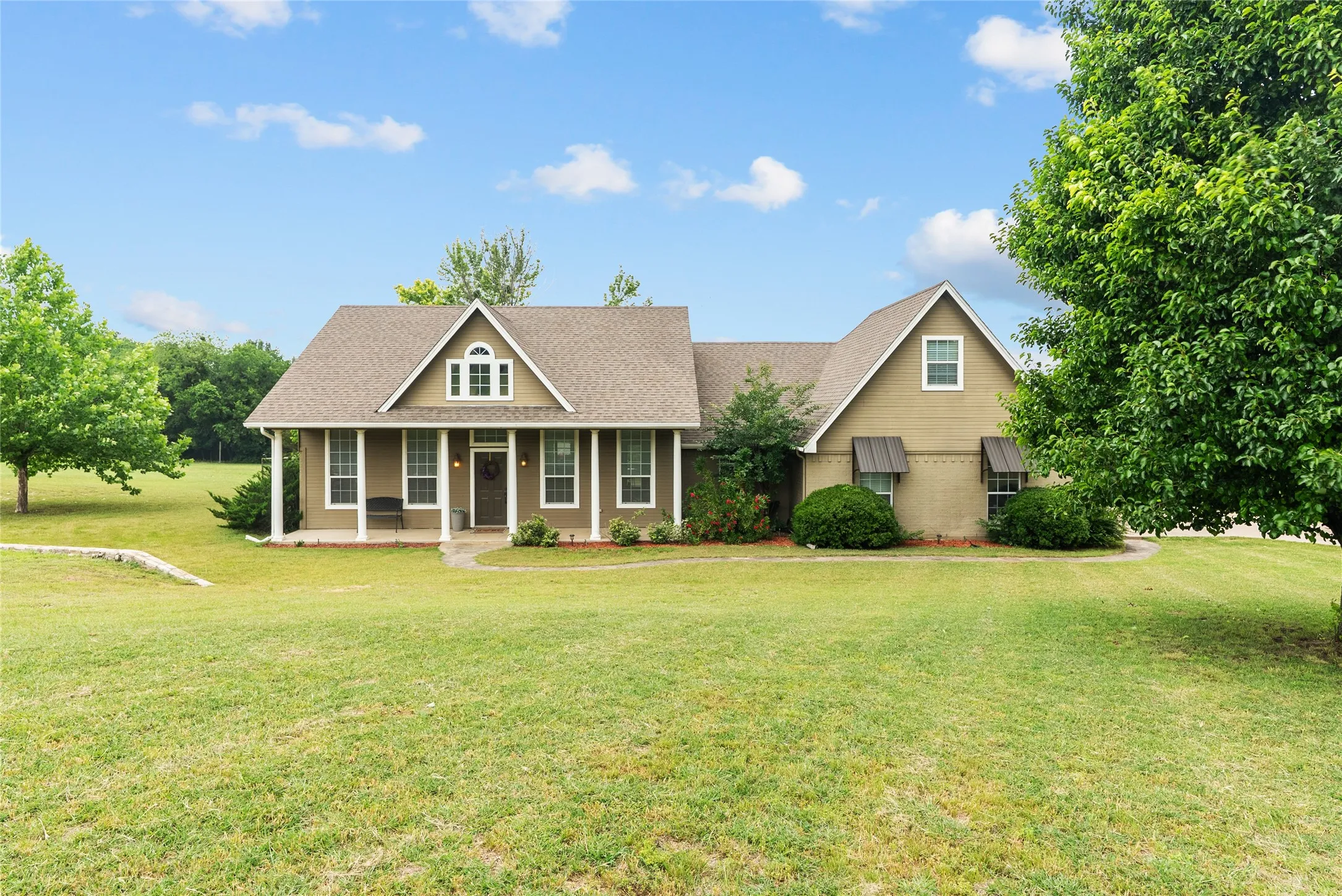 View of front of home with a porch, a front lawn, and a shingled roof