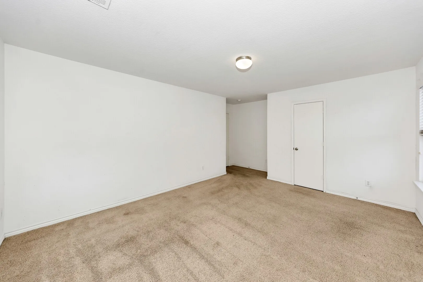 Empty room featuring light carpet and baseboards