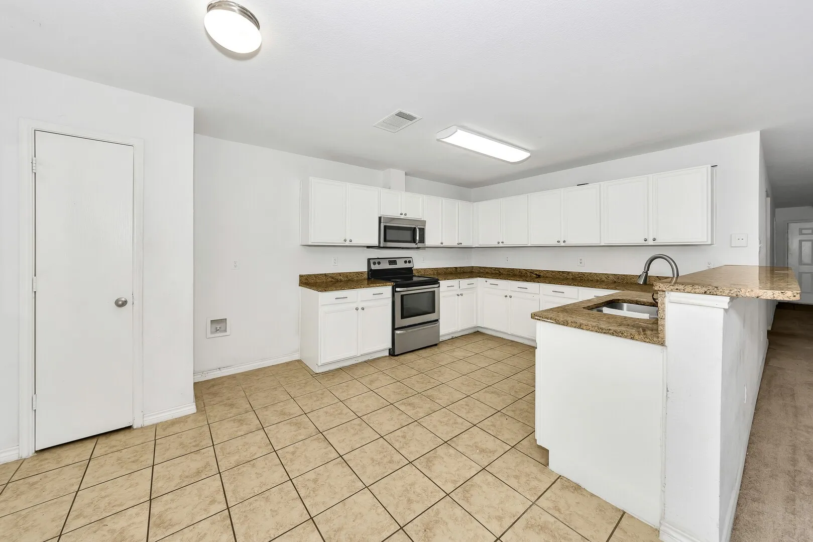 Kitchen featuring appliances with stainless steel finishes, a sink, a peninsula, and white cabinets