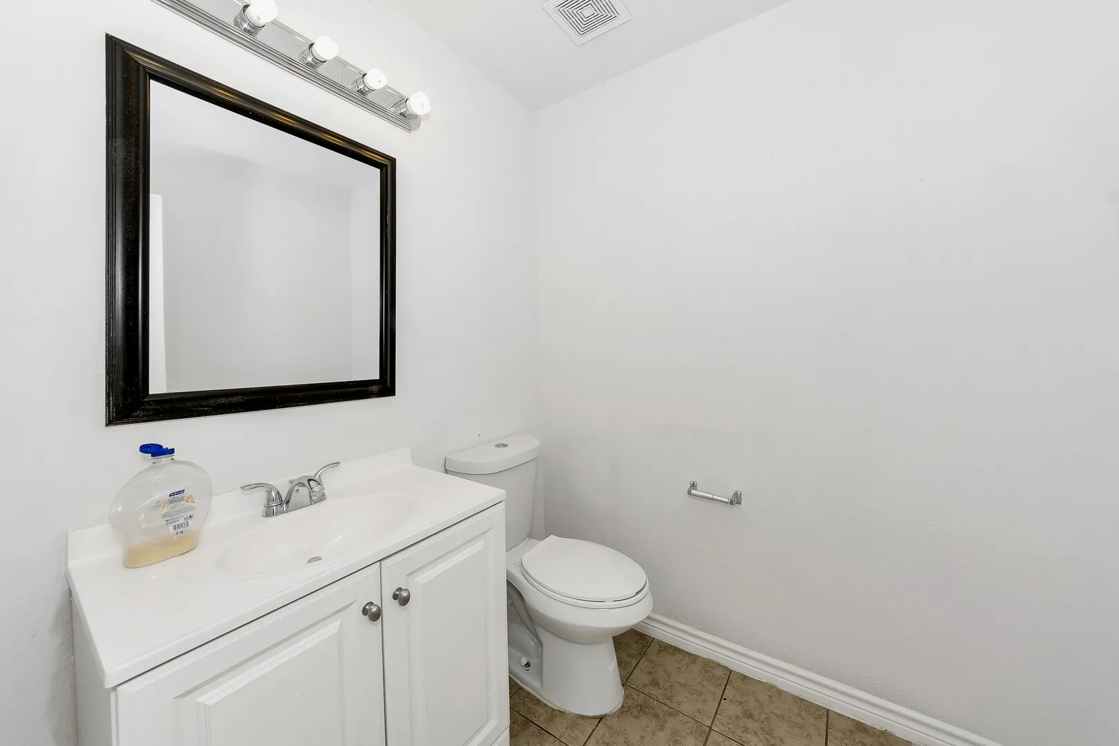 Half bath featuring toilet, vanity, baseboards, and tile patterned floors