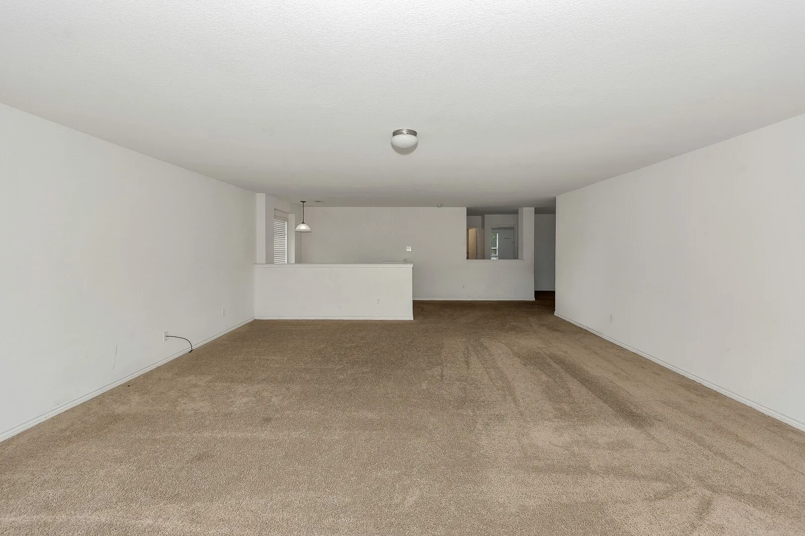 Unfurnished living room with carpet floors and baseboards