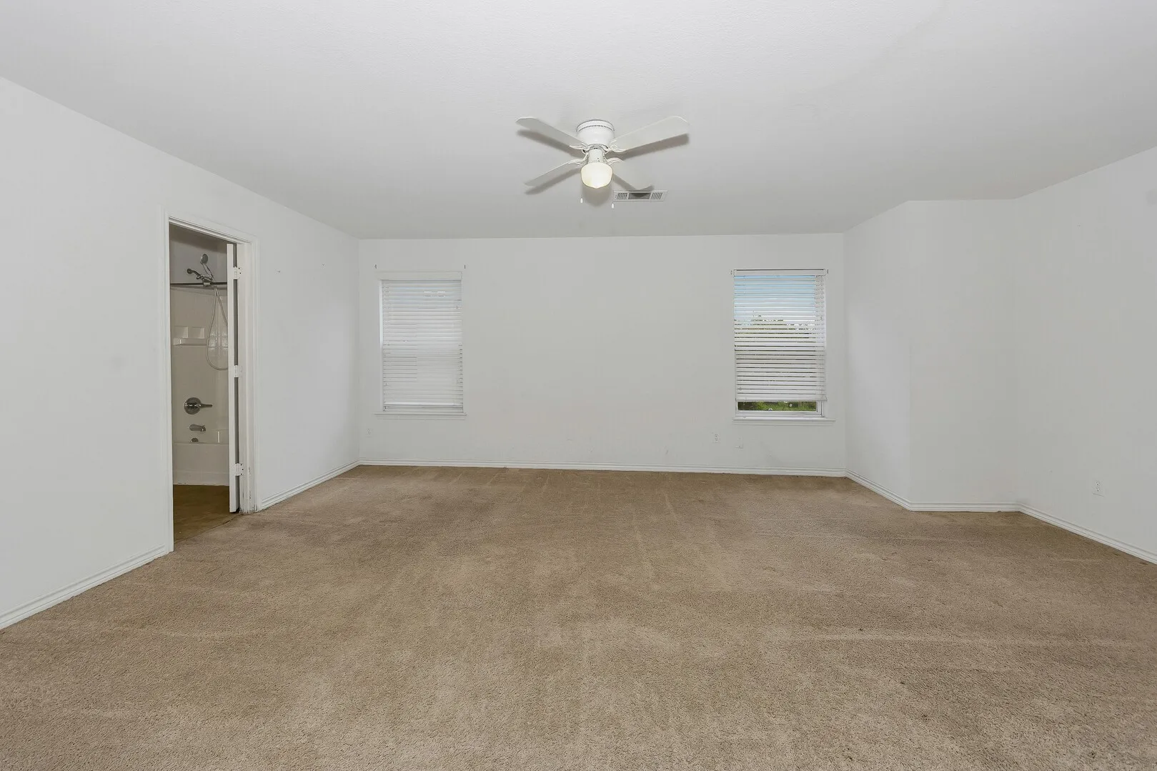 Spare room with light colored carpet, a ceiling fan, and baseboards