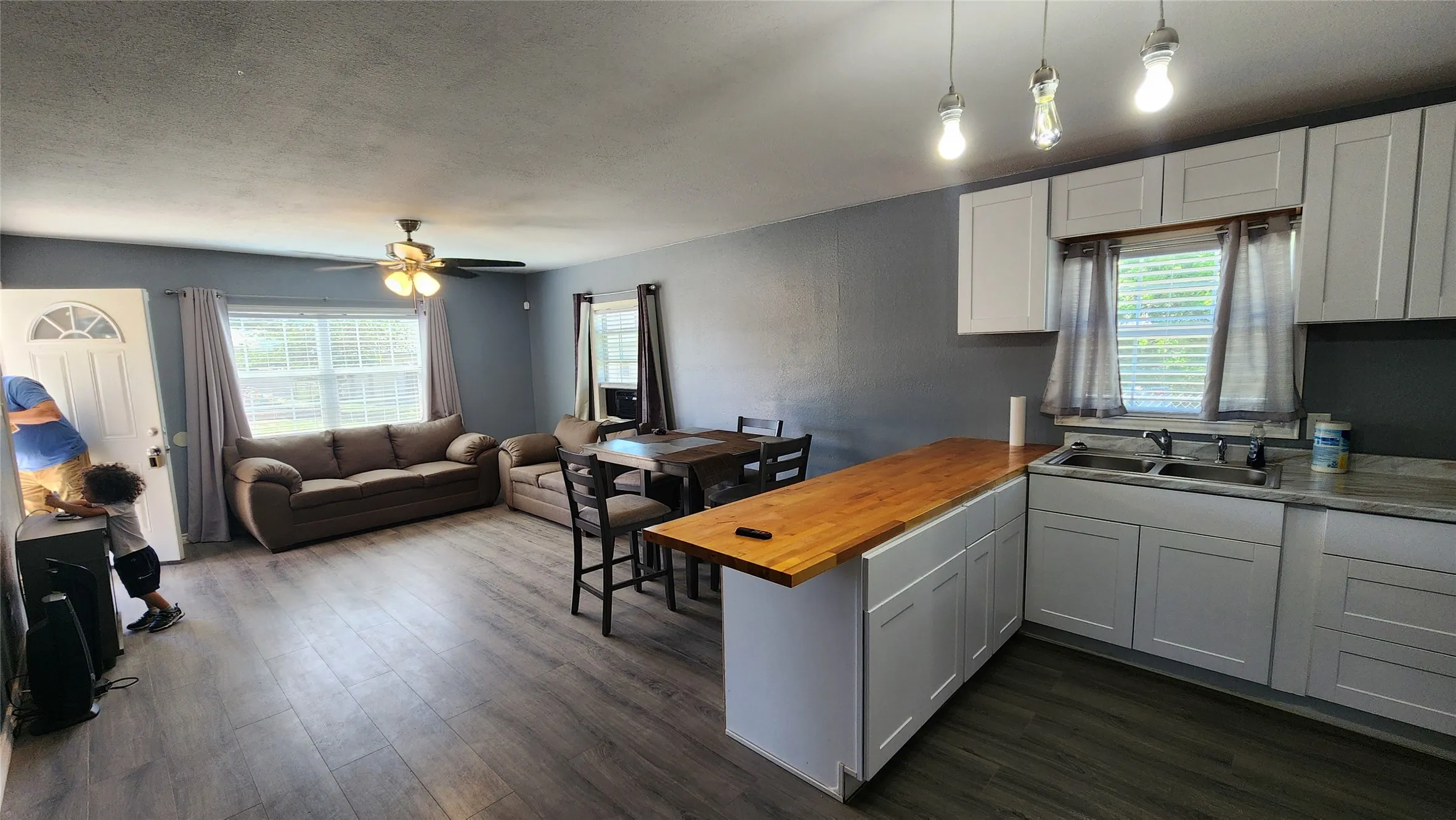 Kitchen featuring a sink, wooden counters, a peninsula, open floor plan, and dark wood-style flooring