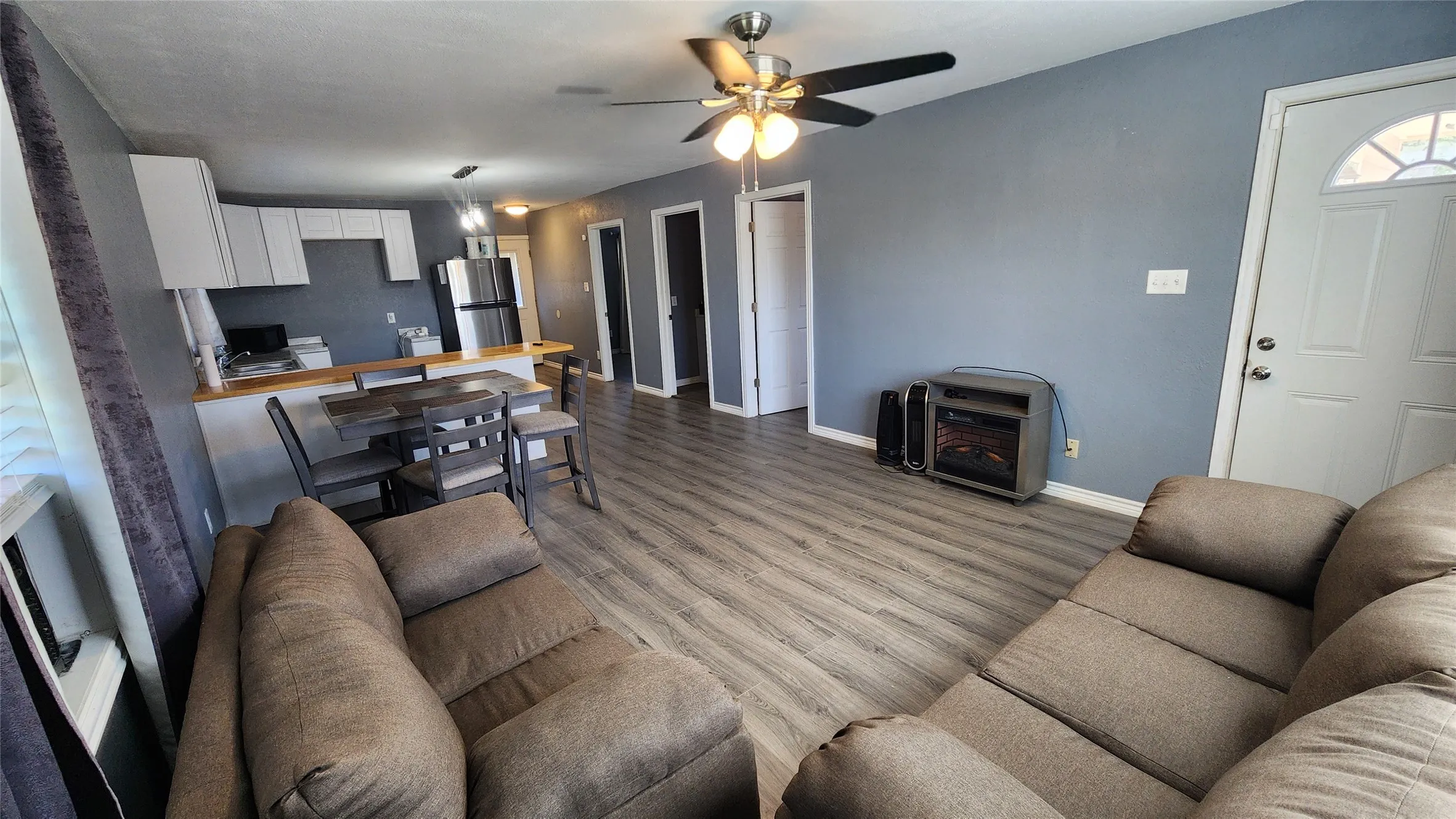 Living area featuring baseboards, ceiling fan, and wood finished floors