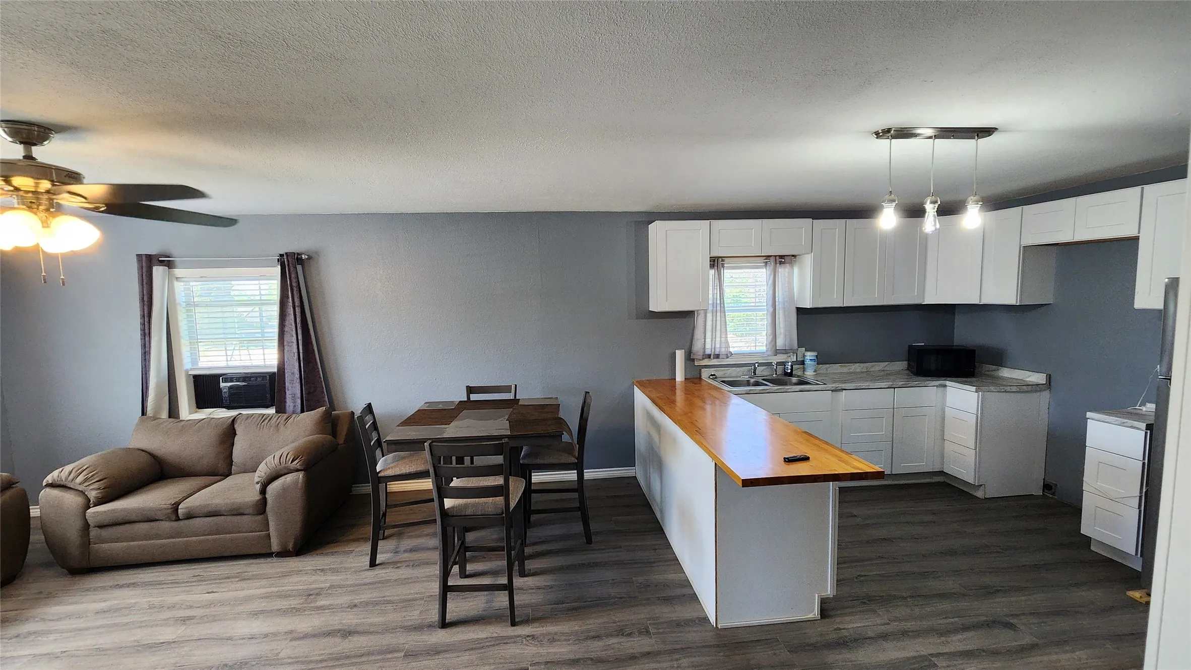 Kitchen featuring butcher block countertops, healthy amount of natural light, white cabinetry, and a textured ceiling