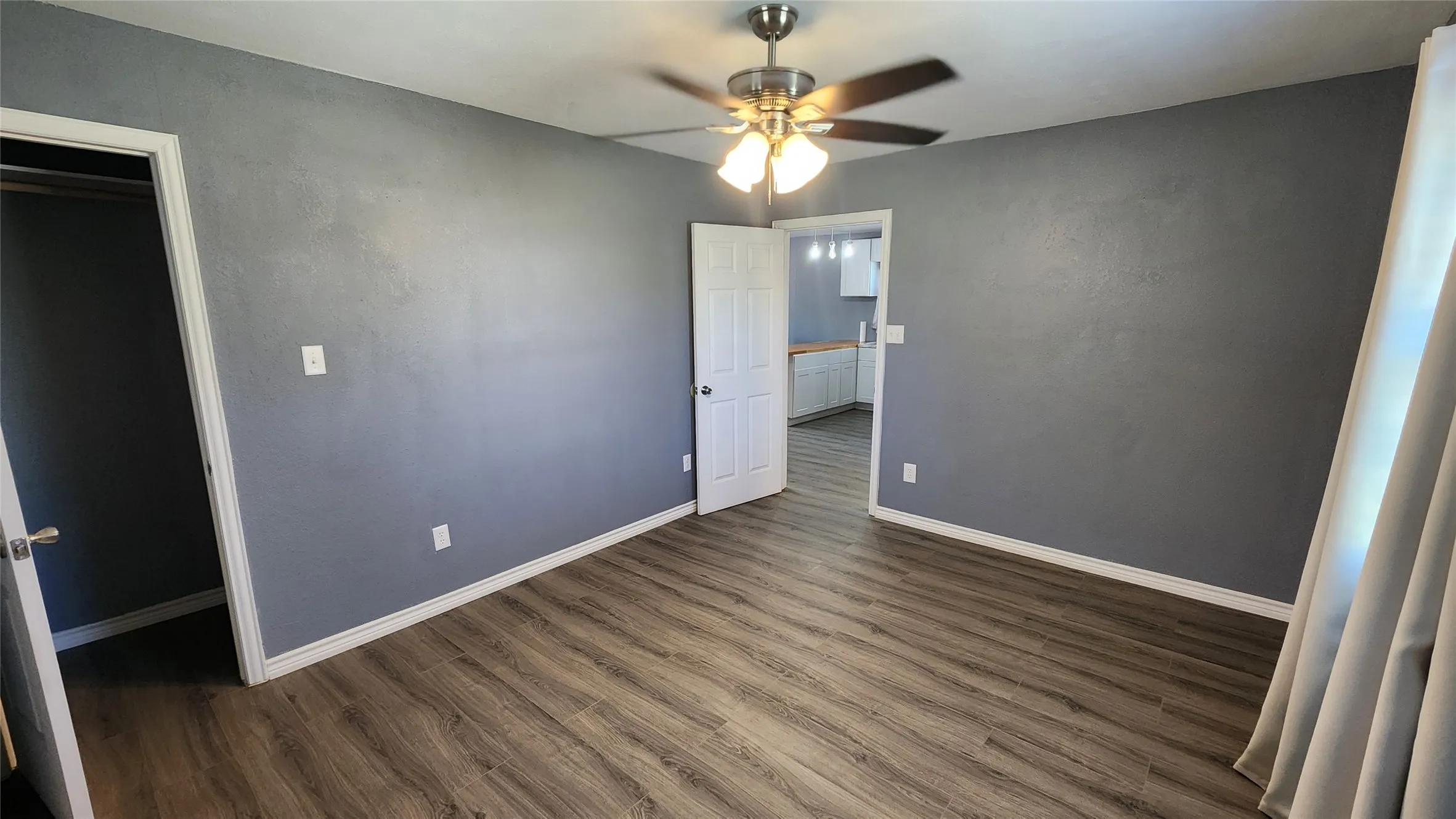 Unfurnished bedroom with dark wood-style floors, baseboards, and a ceiling fan