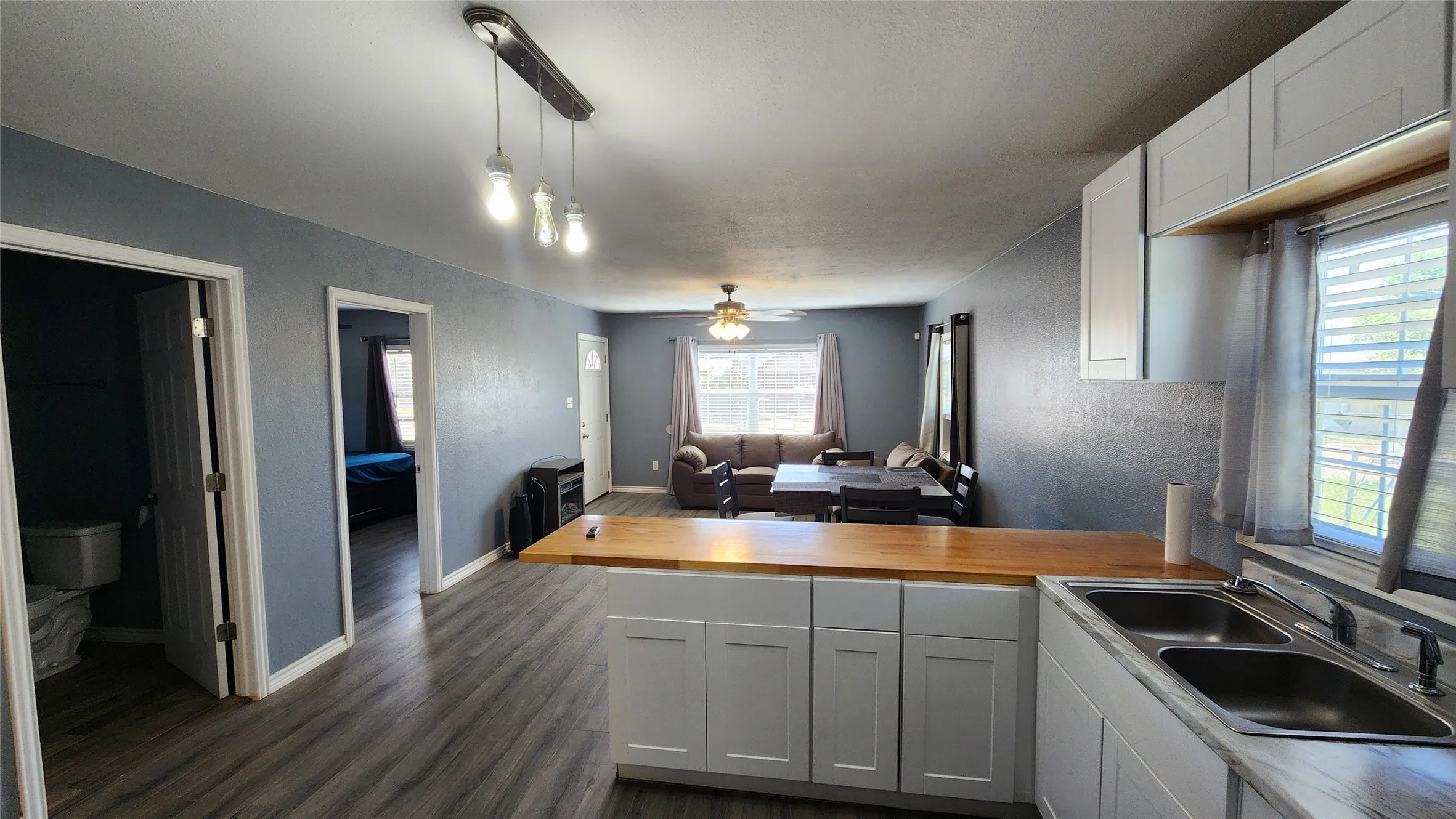 Kitchen with a sink, wooden counters, open floor plan, dark wood-style flooring, and a peninsula