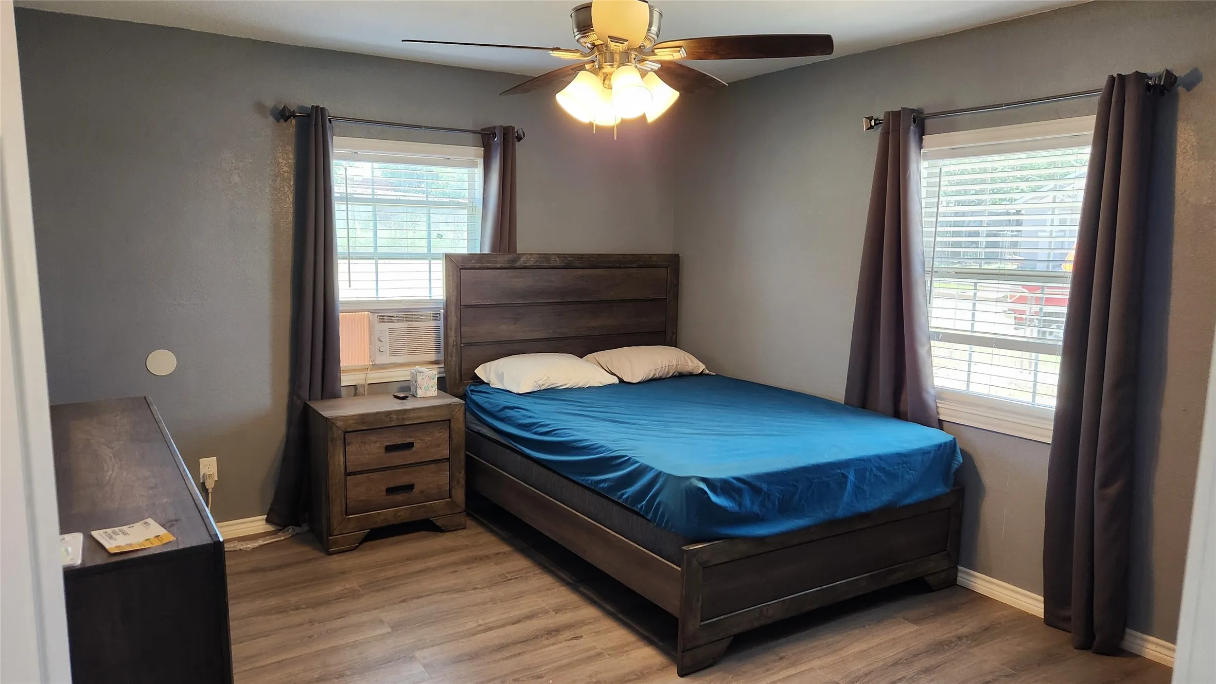 Bedroom with light wood finished floors, baseboards, a ceiling fan, and cooling unit