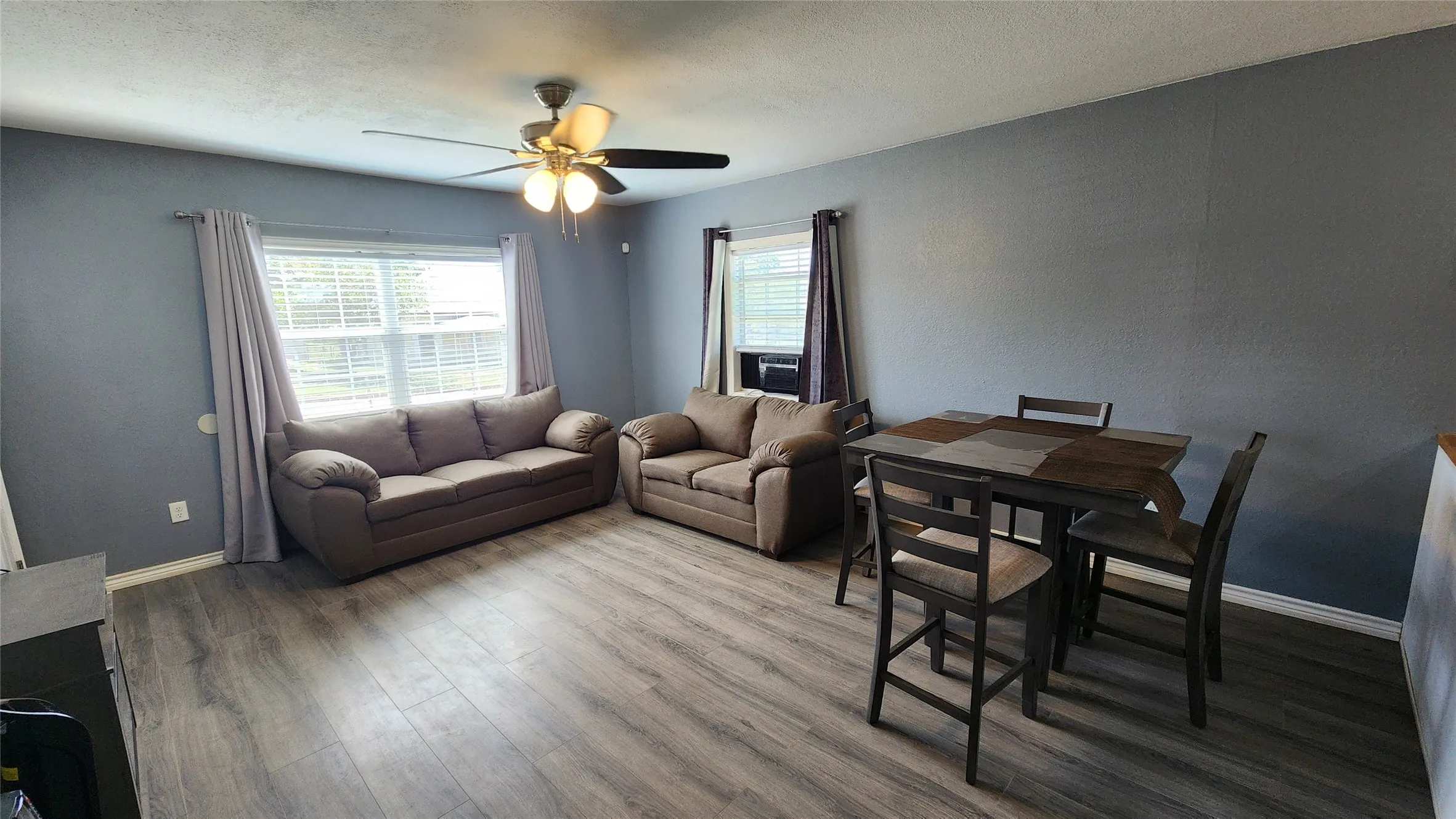 Living area featuring a ceiling fan, wood finished floors, and baseboards