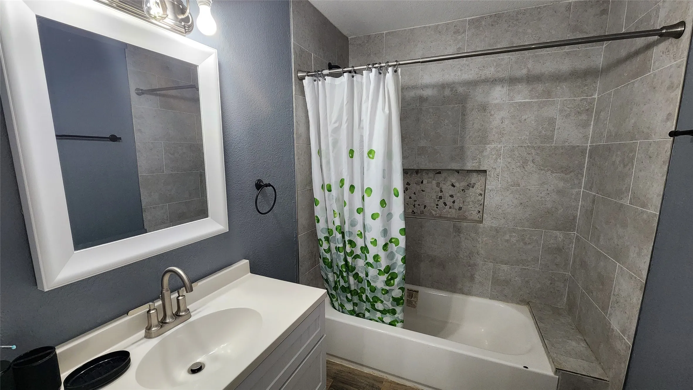 Full bathroom featuring shower / bath combo, vanity, and a textured wall
