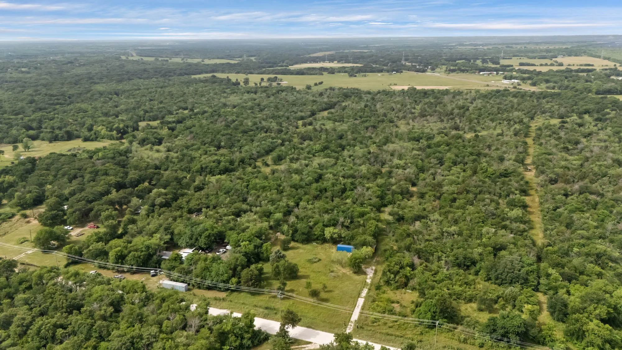 Aerial view of property and surrounding area with a forest