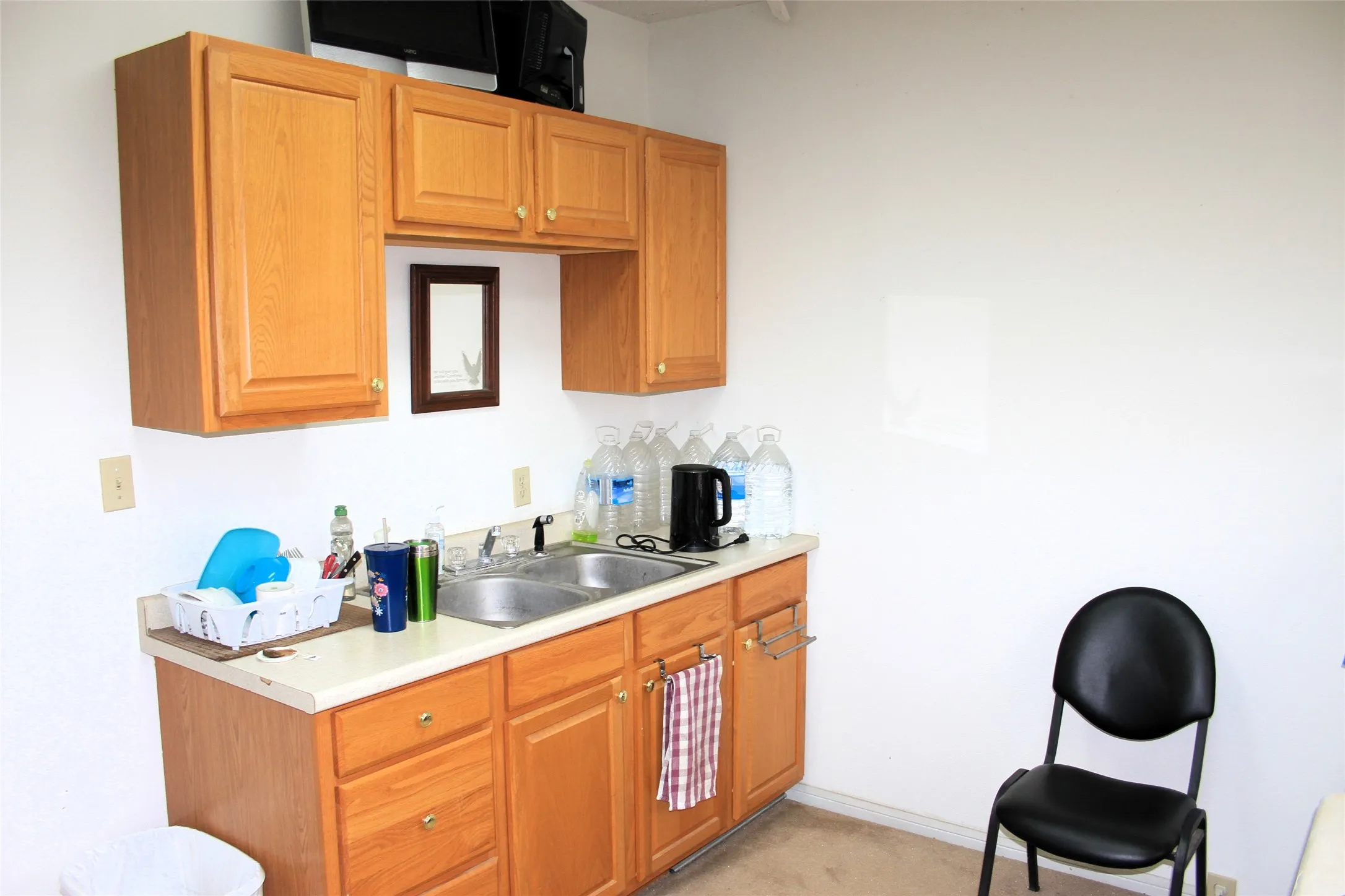 Kitchen featuring a sink, light countertops, and light carpet