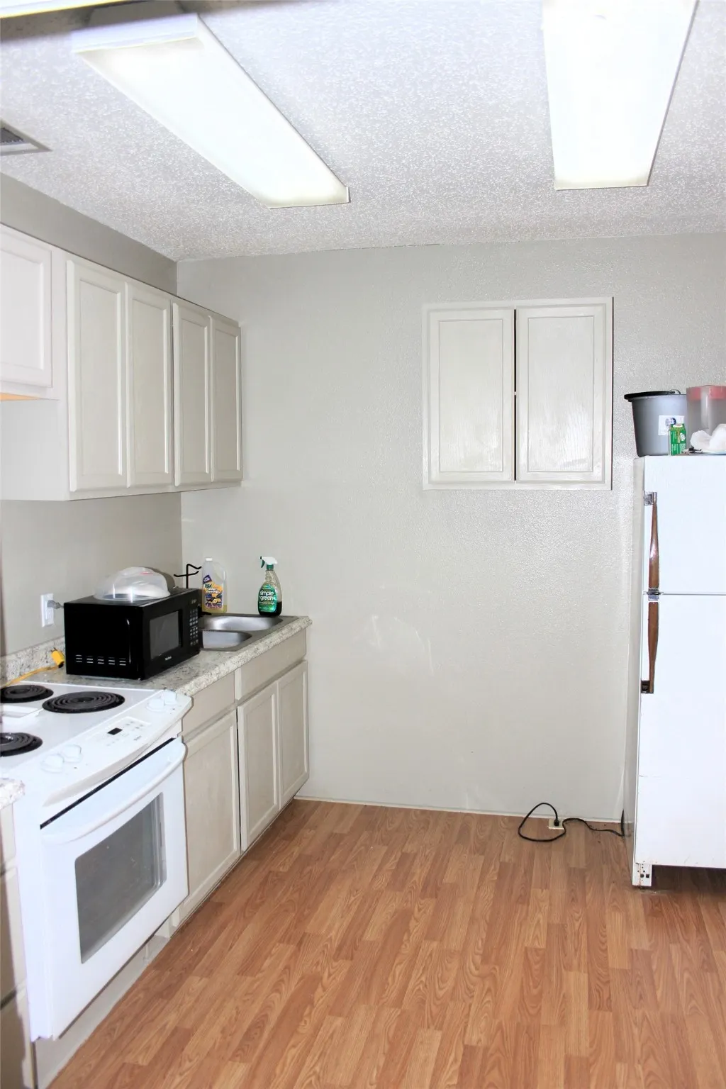 Kitchen featuring white appliances, light countertops, and light wood-style floors
