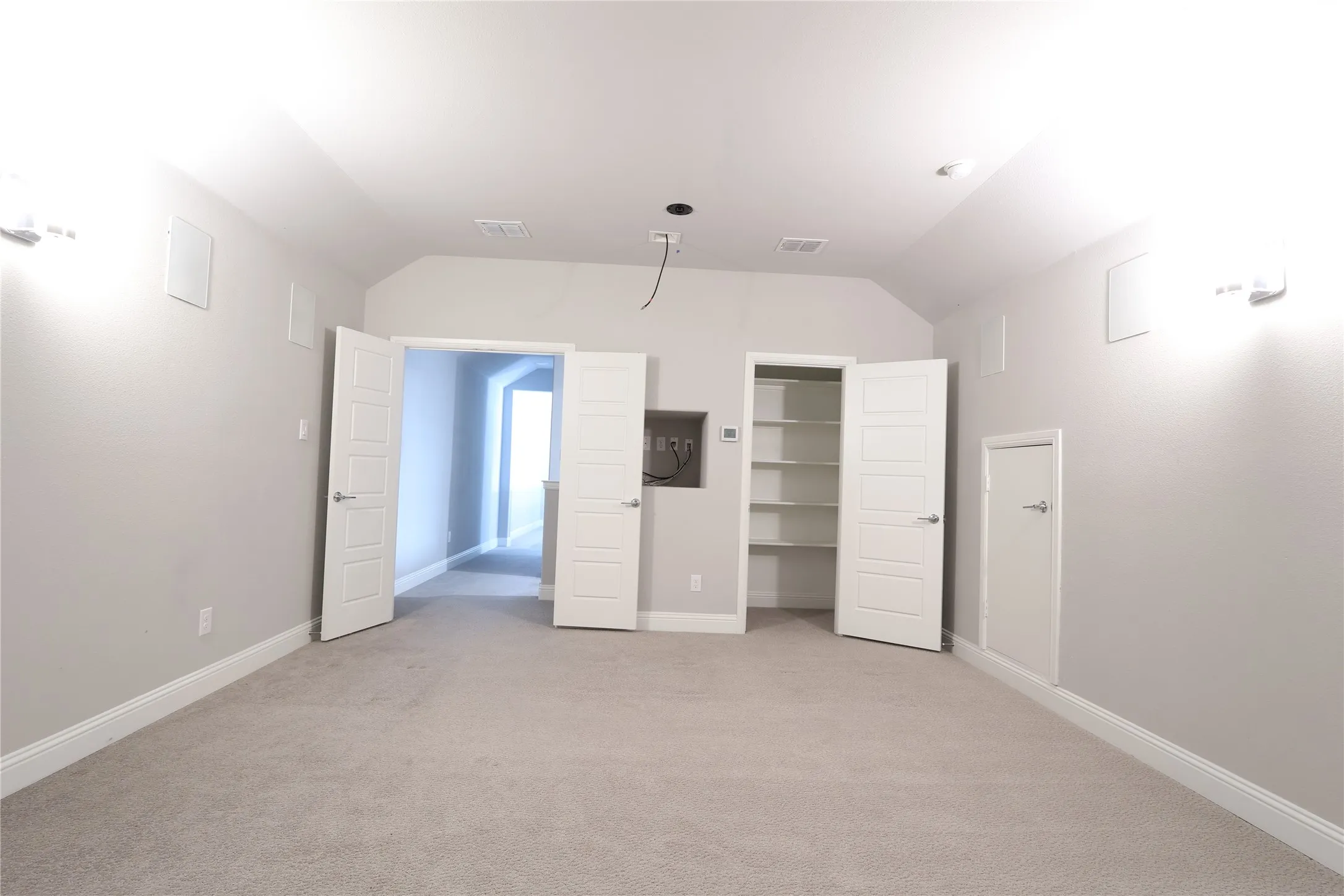Unfurnished bedroom featuring vaulted ceiling, light colored carpet, baseboards, and a walk in closet