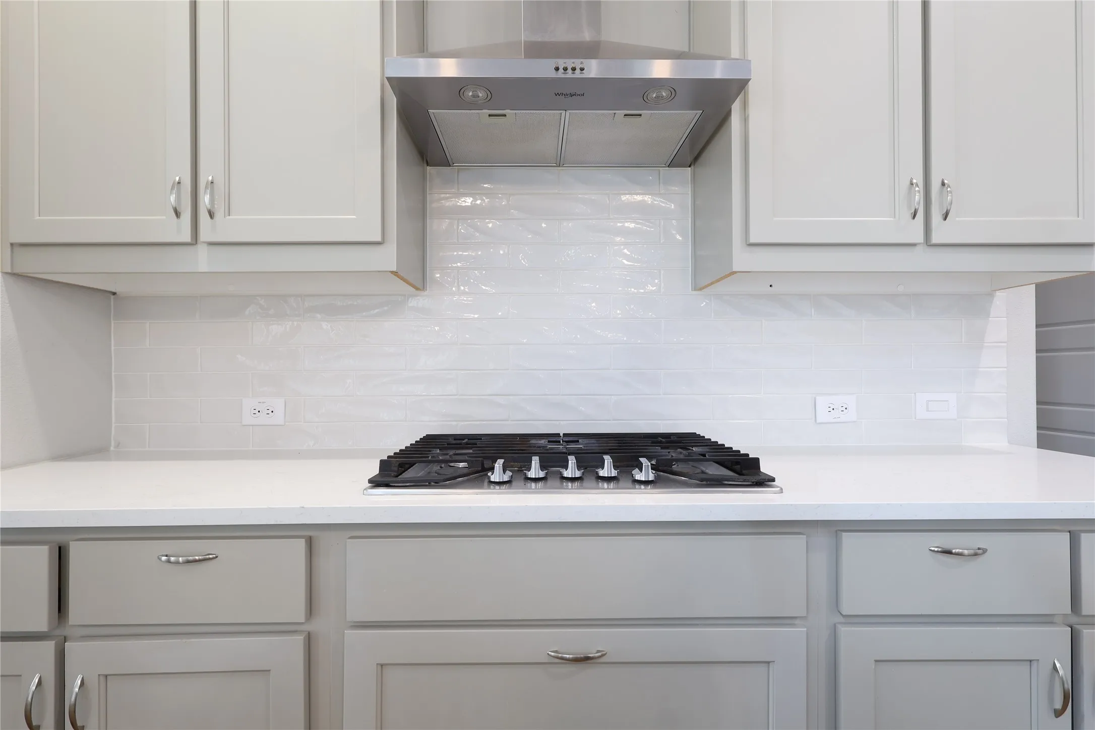 Kitchen with exhaust hood, tasteful backsplash, light countertops, and stainless steel gas stovetop