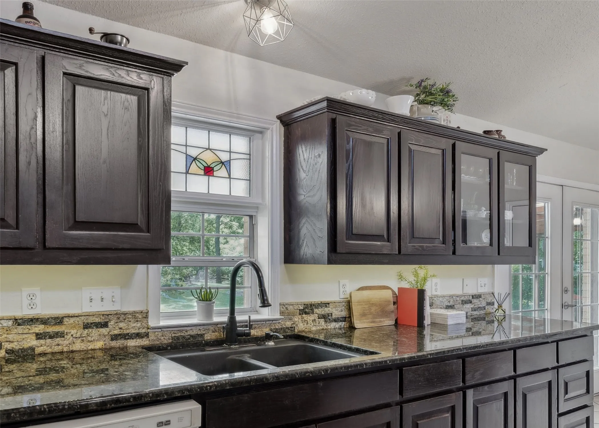 Charming kitchen with rich cabinetry, granite countertops, and a cozy breakfast nook—brightened by natural light and backyard views.