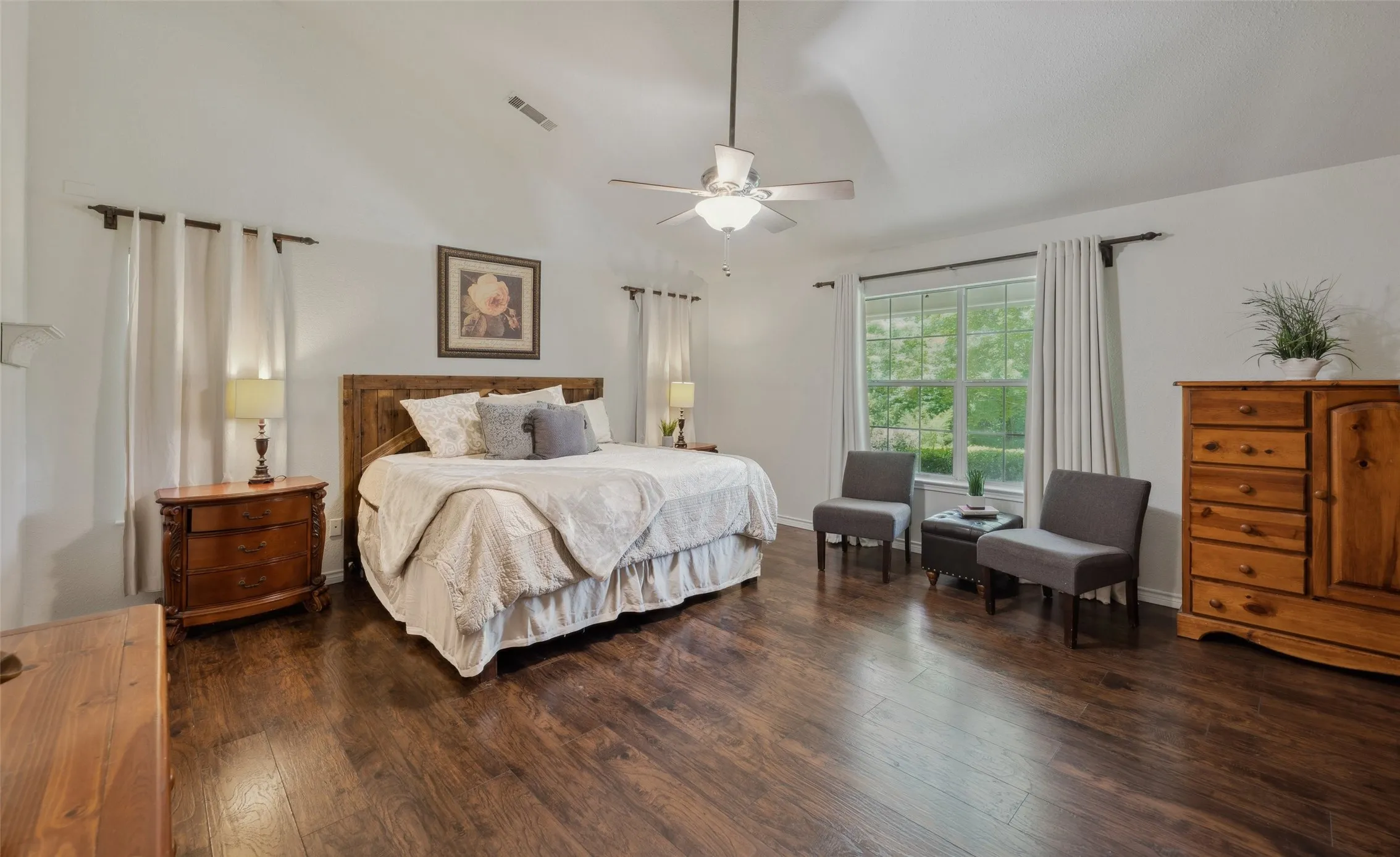 Oversized primary suite with rich wood flooring, tranquil views, and plenty of space to unwind or add a cozy sitting area