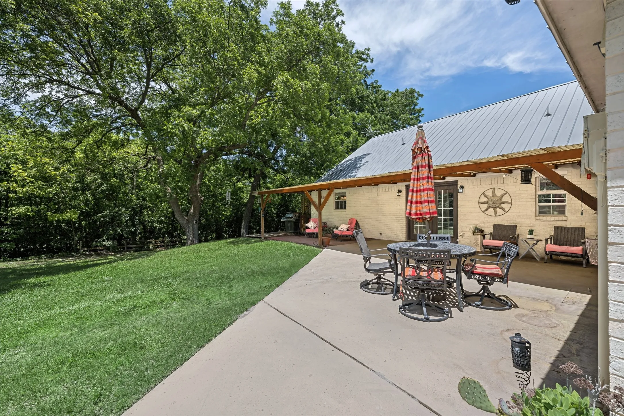 Scenic covered patio with serene views of the tree-lined property—ideal for relaxing, coffee, or enjoying the peaceful outdoors.