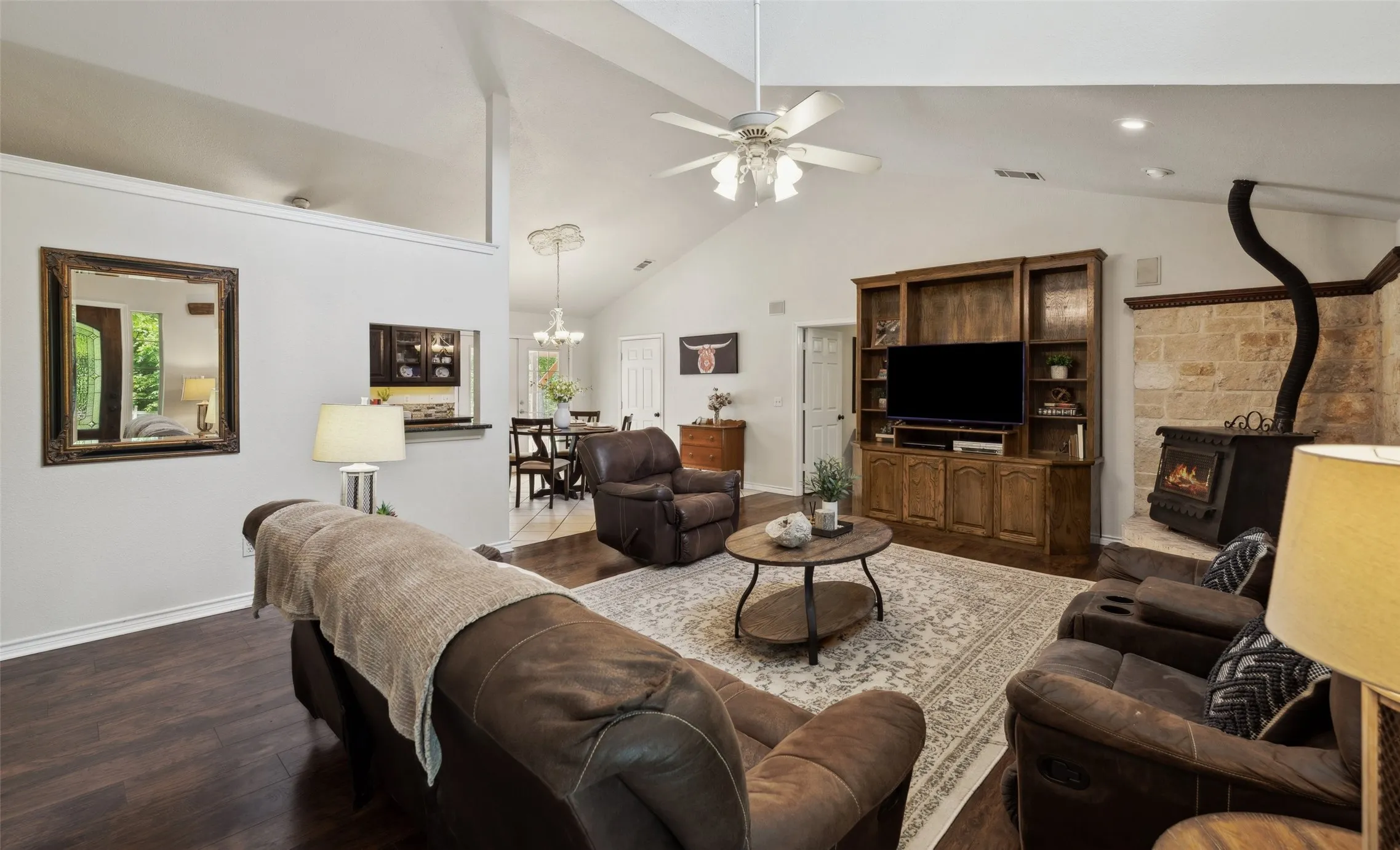 Light-filled living room with soaring ceilings, a grand window, cozy stove fireplace, and built-in media center—perfect for relaxed gatherings