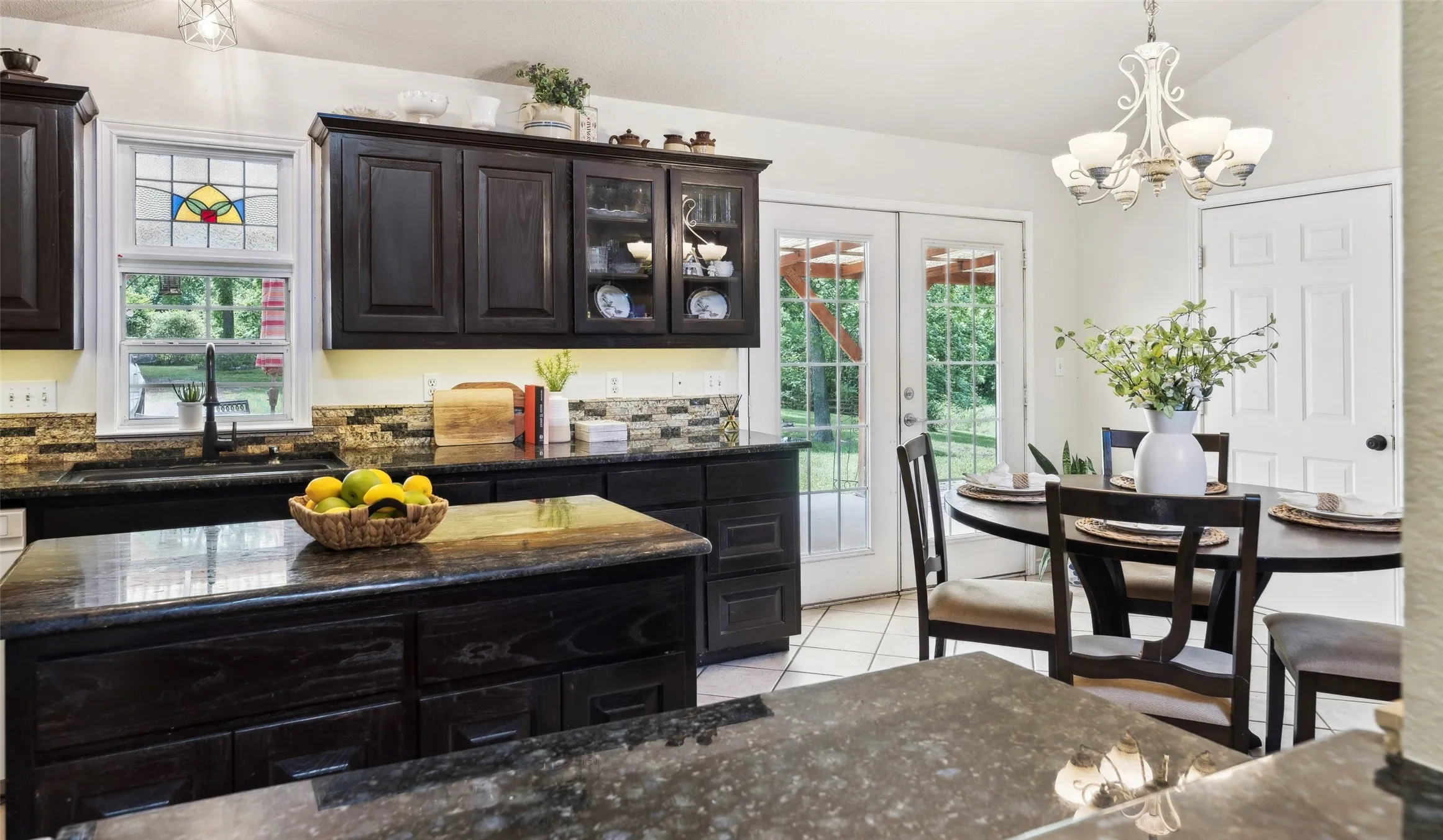 Charming kitchen with rich cabinetry, granite countertops, and a cozy breakfast nook—brightened by natural light and backyard views.