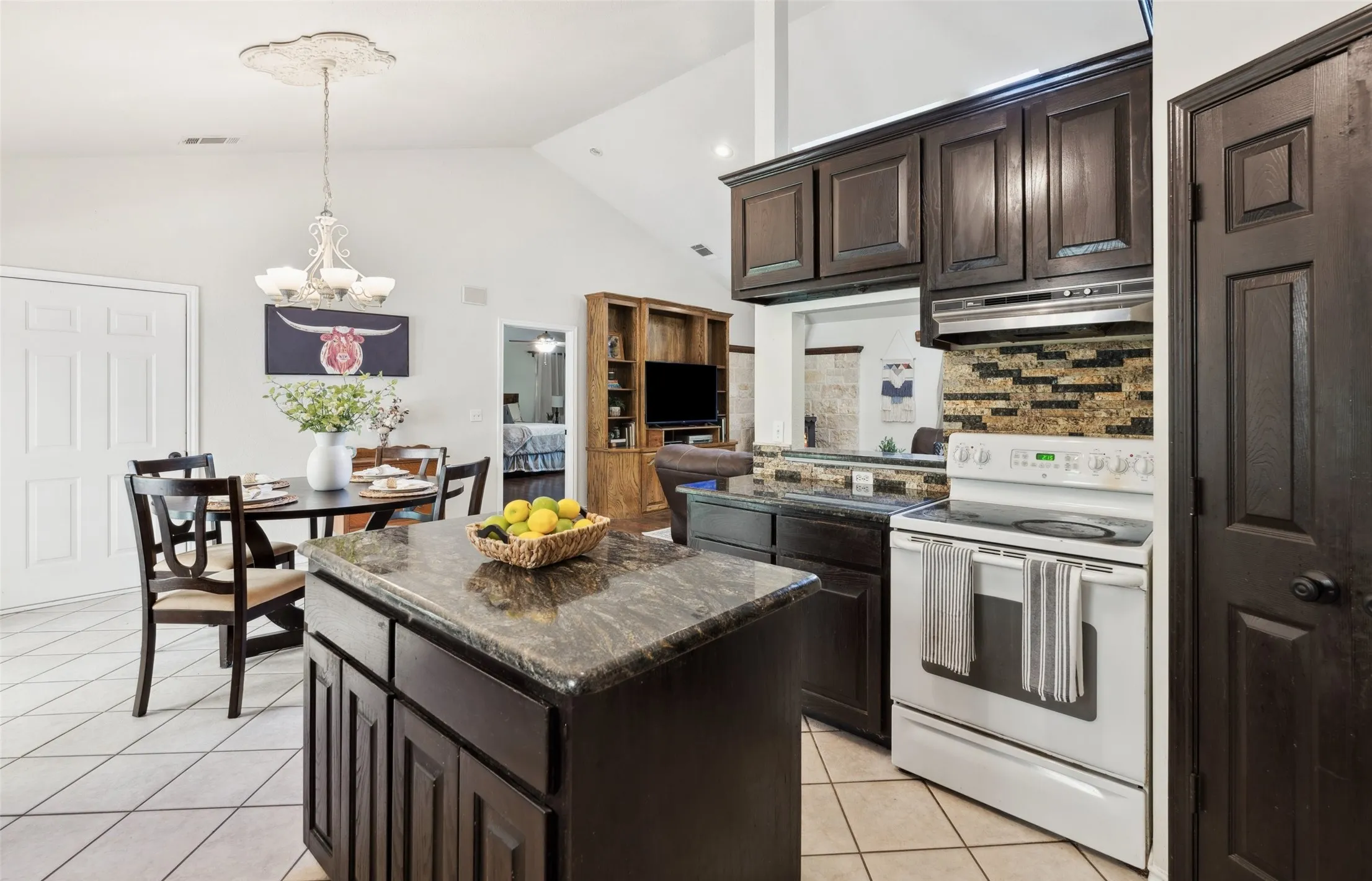 Charming kitchen with rich cabinetry, granite countertops, and a cozy breakfast nook—brightened by natural light and backyard views.