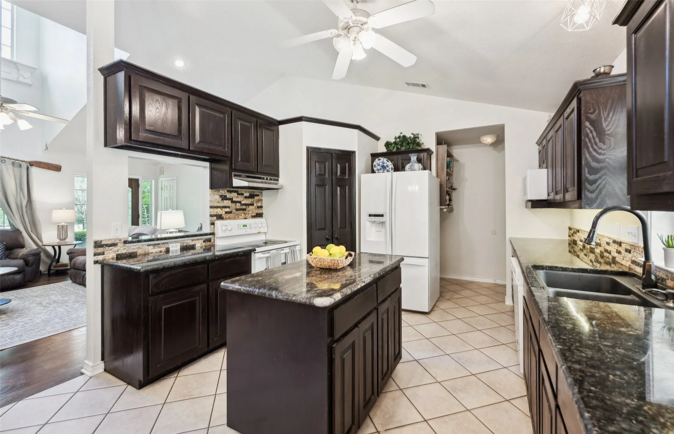 Charming kitchen with rich cabinetry, granite countertops, and a cozy breakfast nook—brightened by natural light and backyard views.