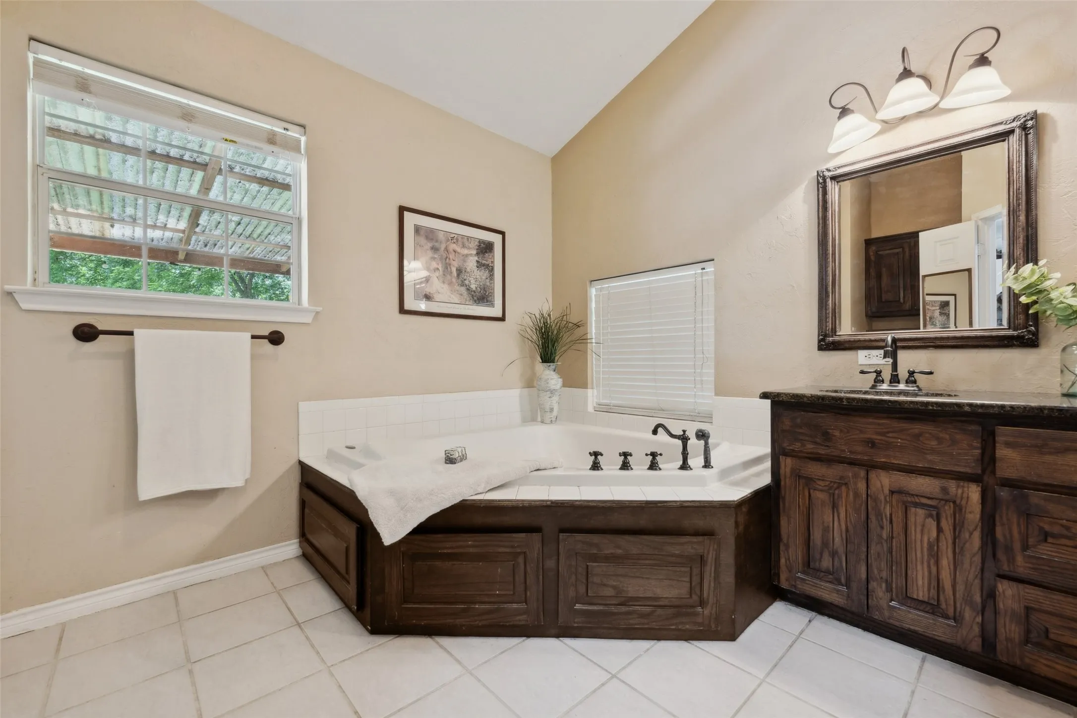 Jetted tub and separate glass-enclosed shower, complemented by warm cabinetry with ample storage and an oversized primary closet.