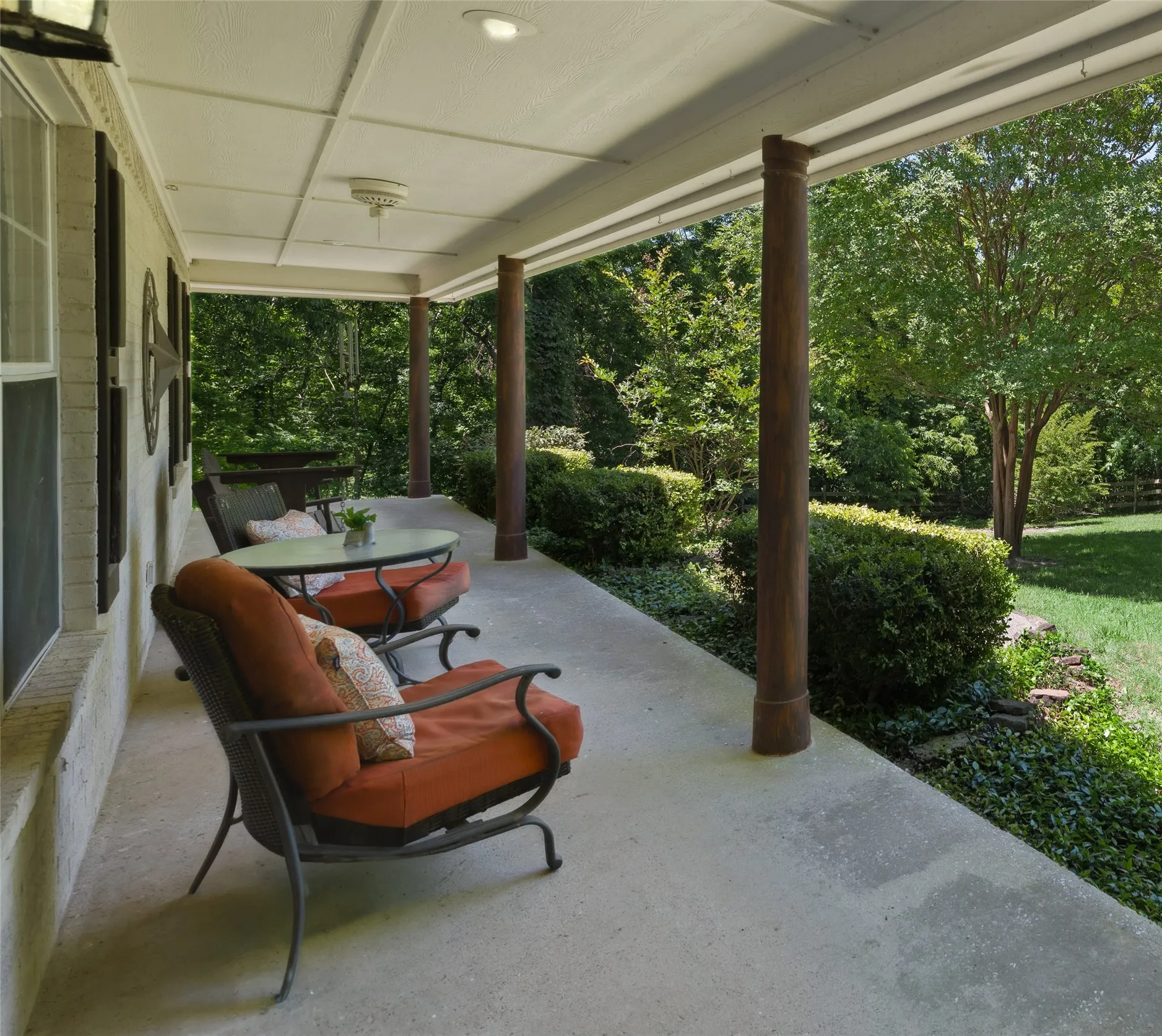 Scenic covered patio with serene views of the tree-lined property—ideal for relaxing, coffee, or enjoying the peaceful outdoors.