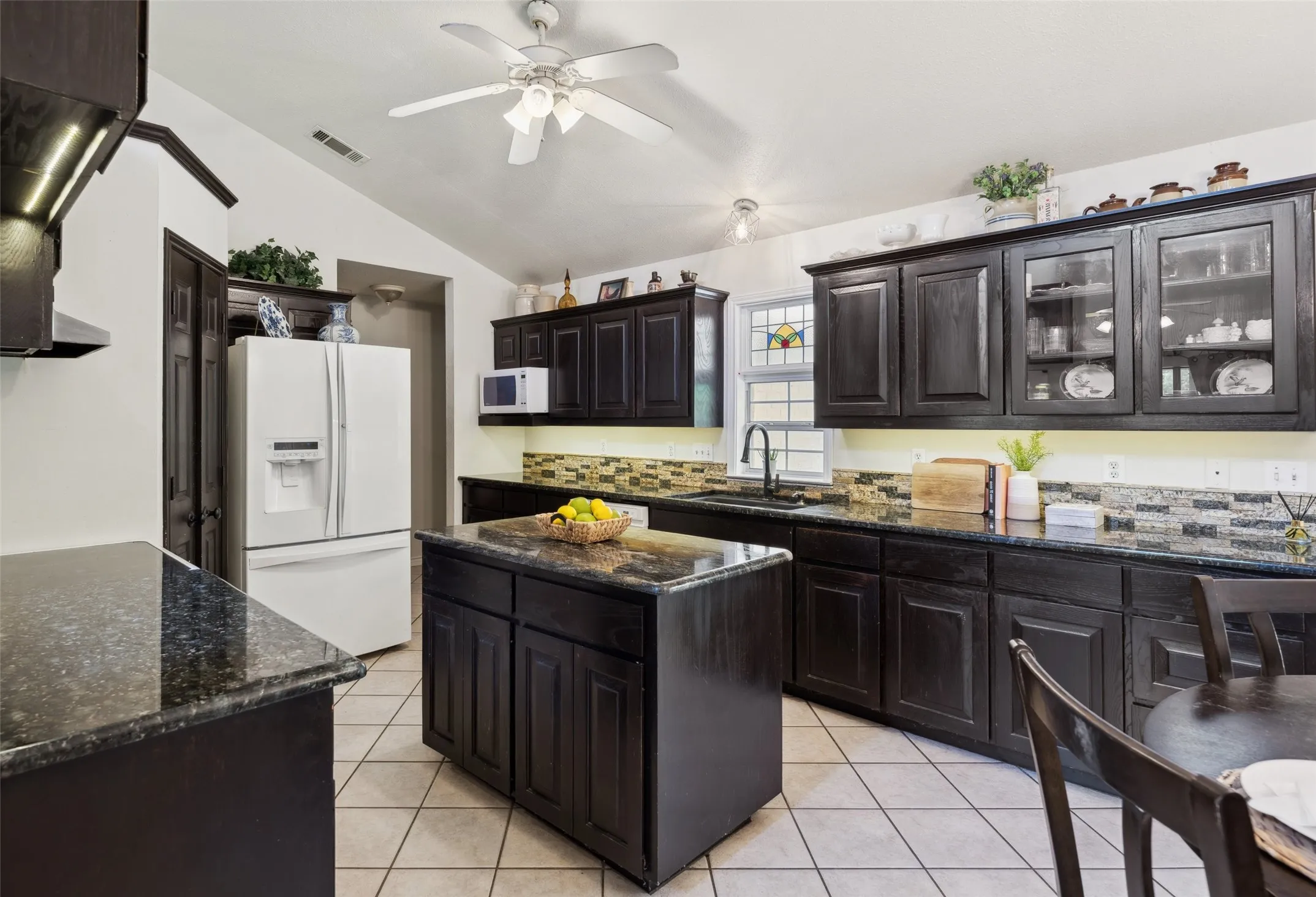 Charming kitchen with rich cabinetry, granite countertops, and a cozy breakfast nook—brightened by natural light and backyard views.