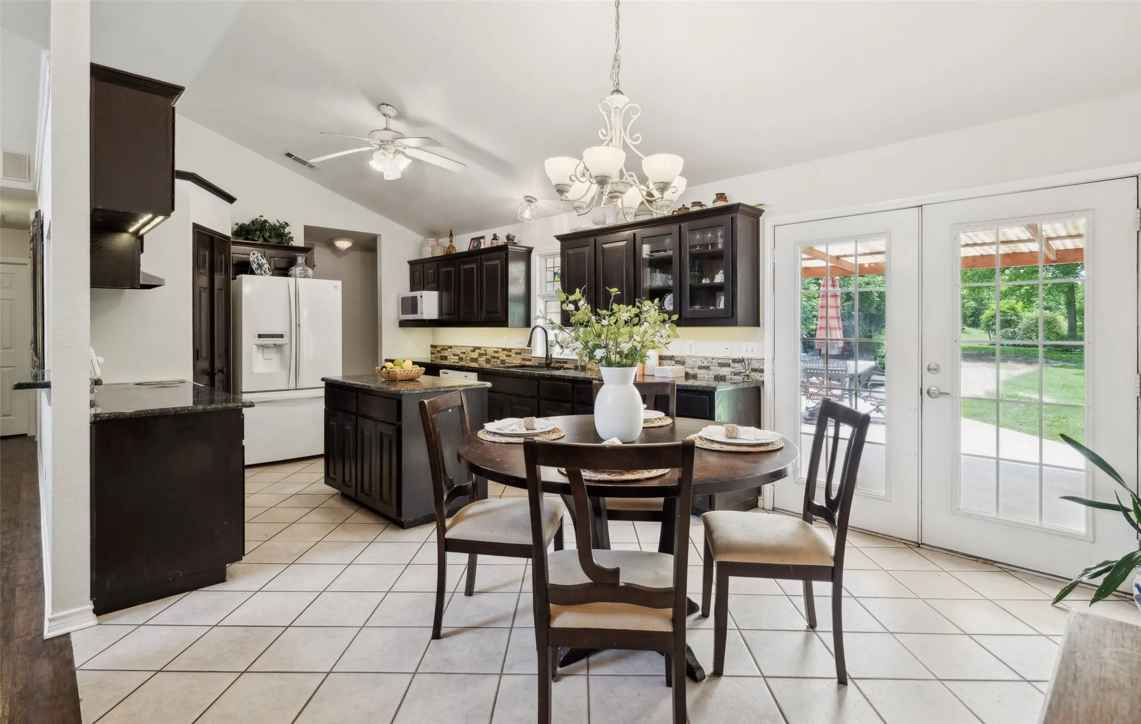 Charming kitchen with rich cabinetry, granite countertops, and a cozy breakfast nook—brightened by natural light and backyard views.