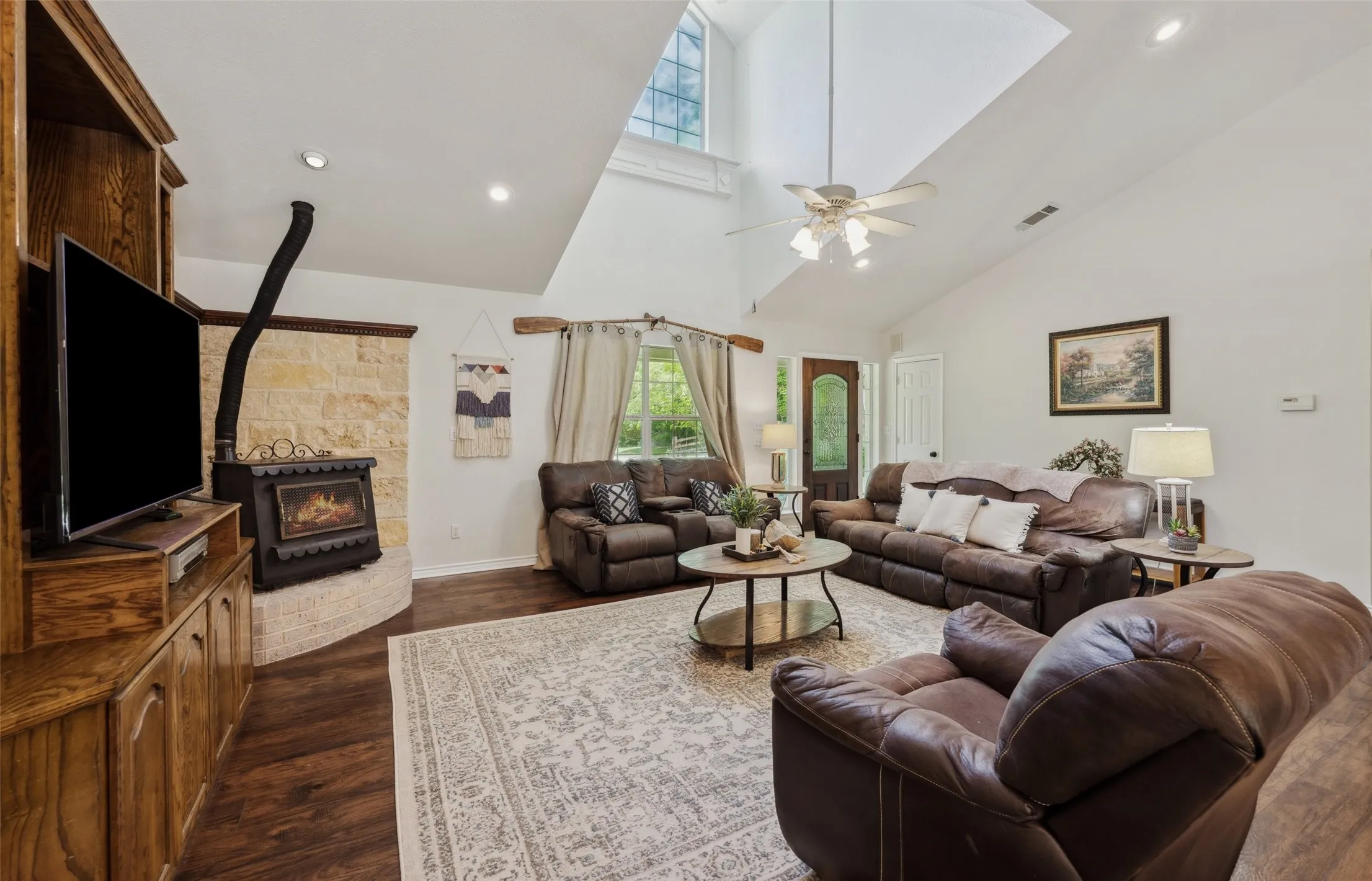 Light-filled living room with soaring ceilings, a grand window, cozy stove fireplace, and built-in media center—perfect for relaxed gatherings