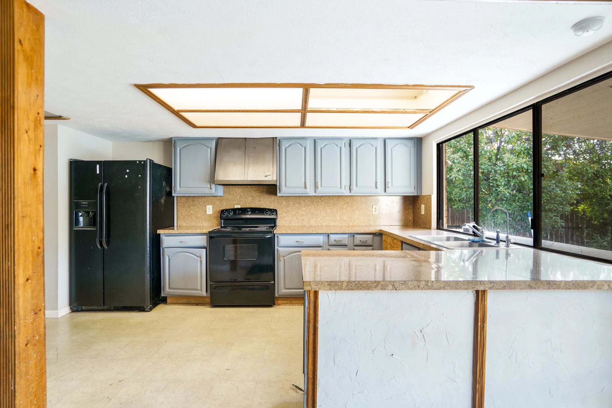Kitchen featuring black appliances, a sink, decorative backsplash, and gray cabinetry