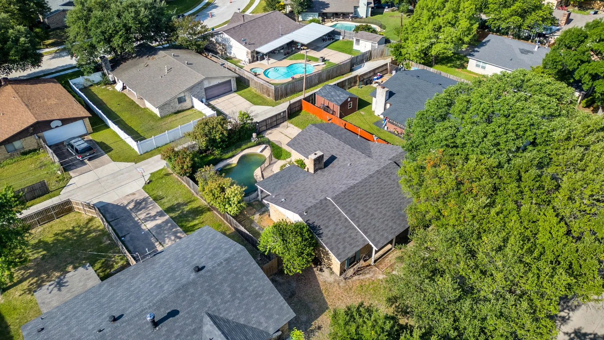Aerial view of property and surrounding area featuring a pool and nearby suburban area