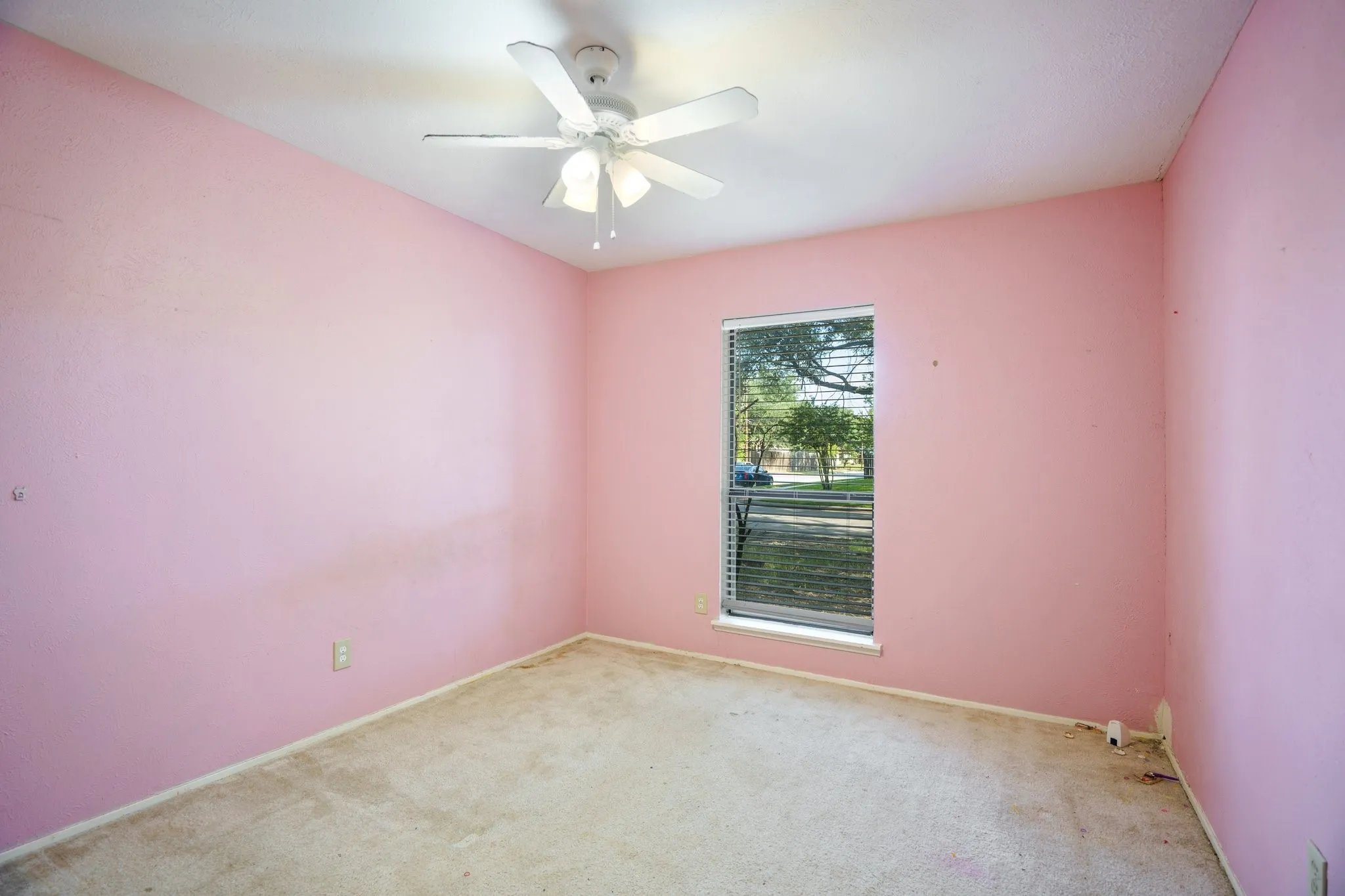 Carpeted empty room featuring ceiling fan and baseboards