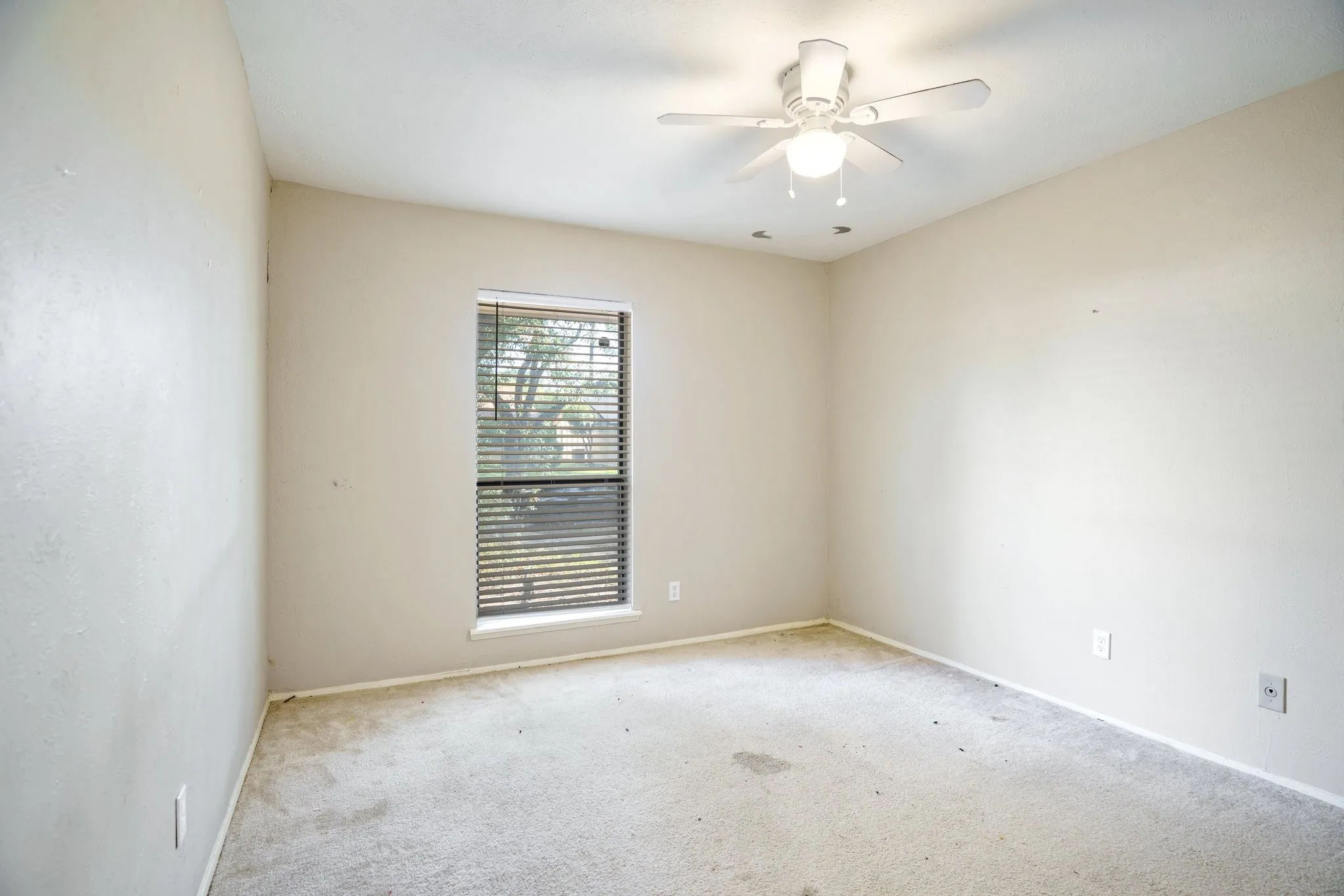 Carpeted spare room with ceiling fan and baseboards