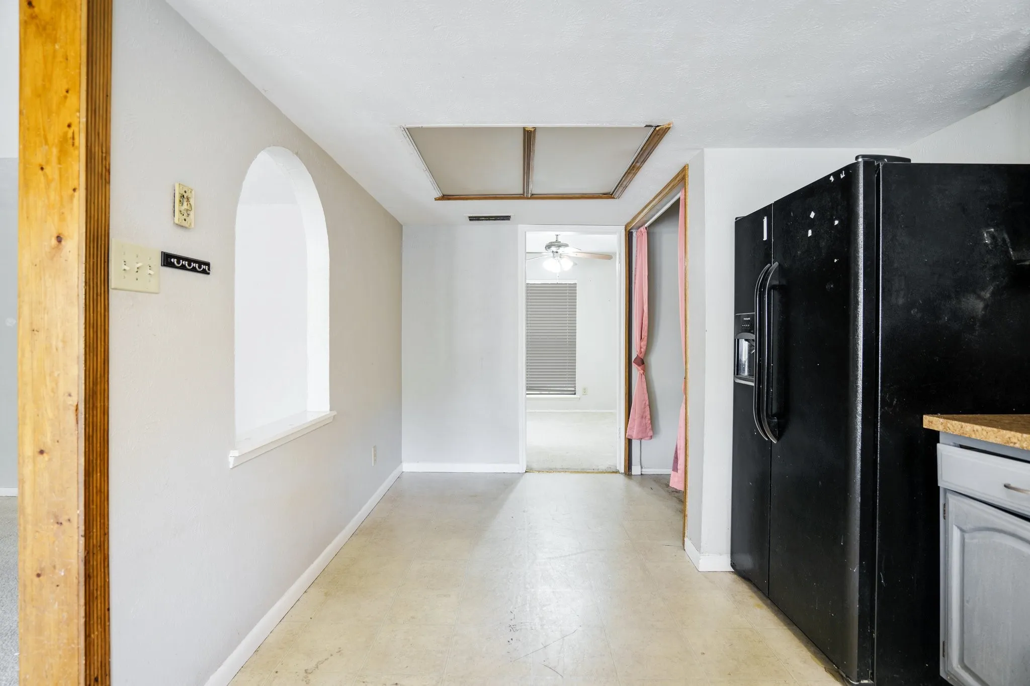 Kitchen featuring black fridge with ice dispenser, baseboards, concrete flooring, and arched walkways