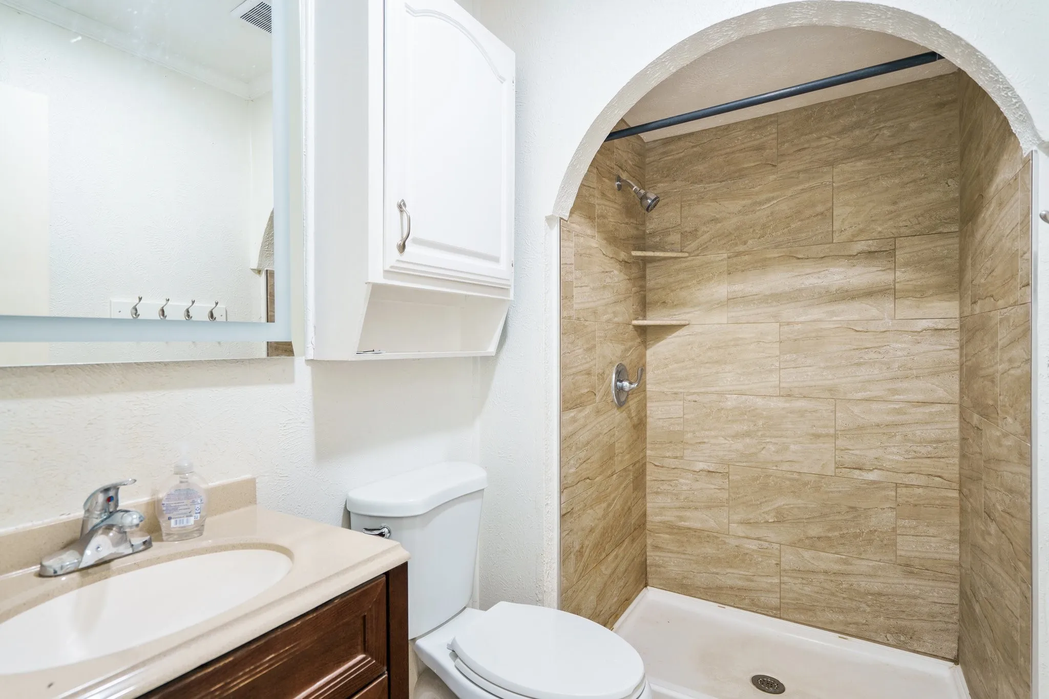 Full bath featuring toilet, vanity, and a tile shower