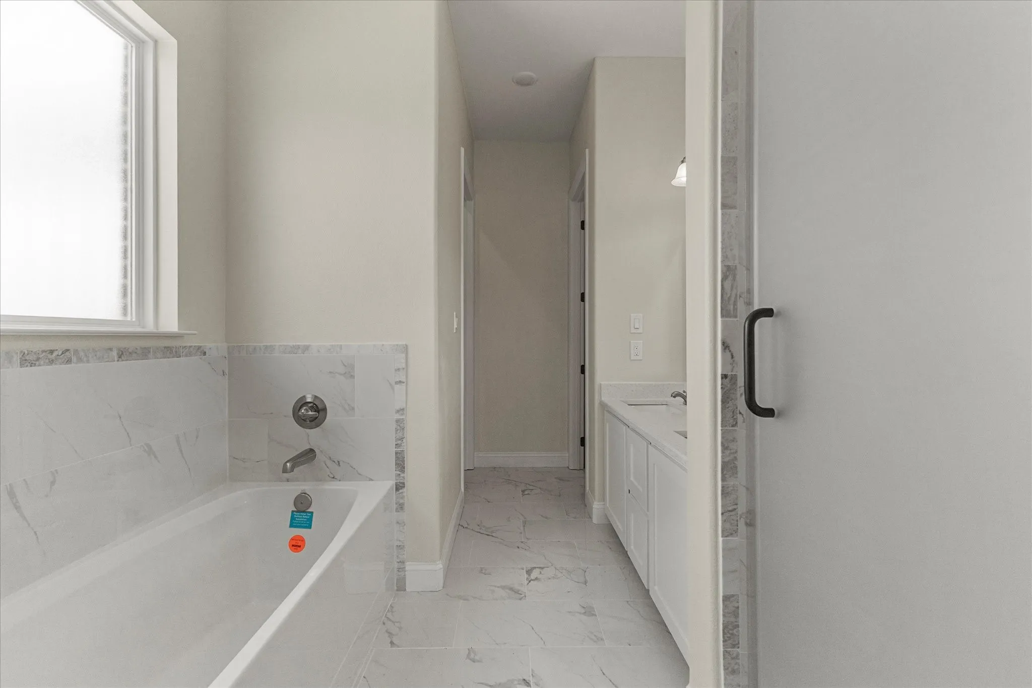 Bathroom featuring marble finish floors, a garden tub, and vanity